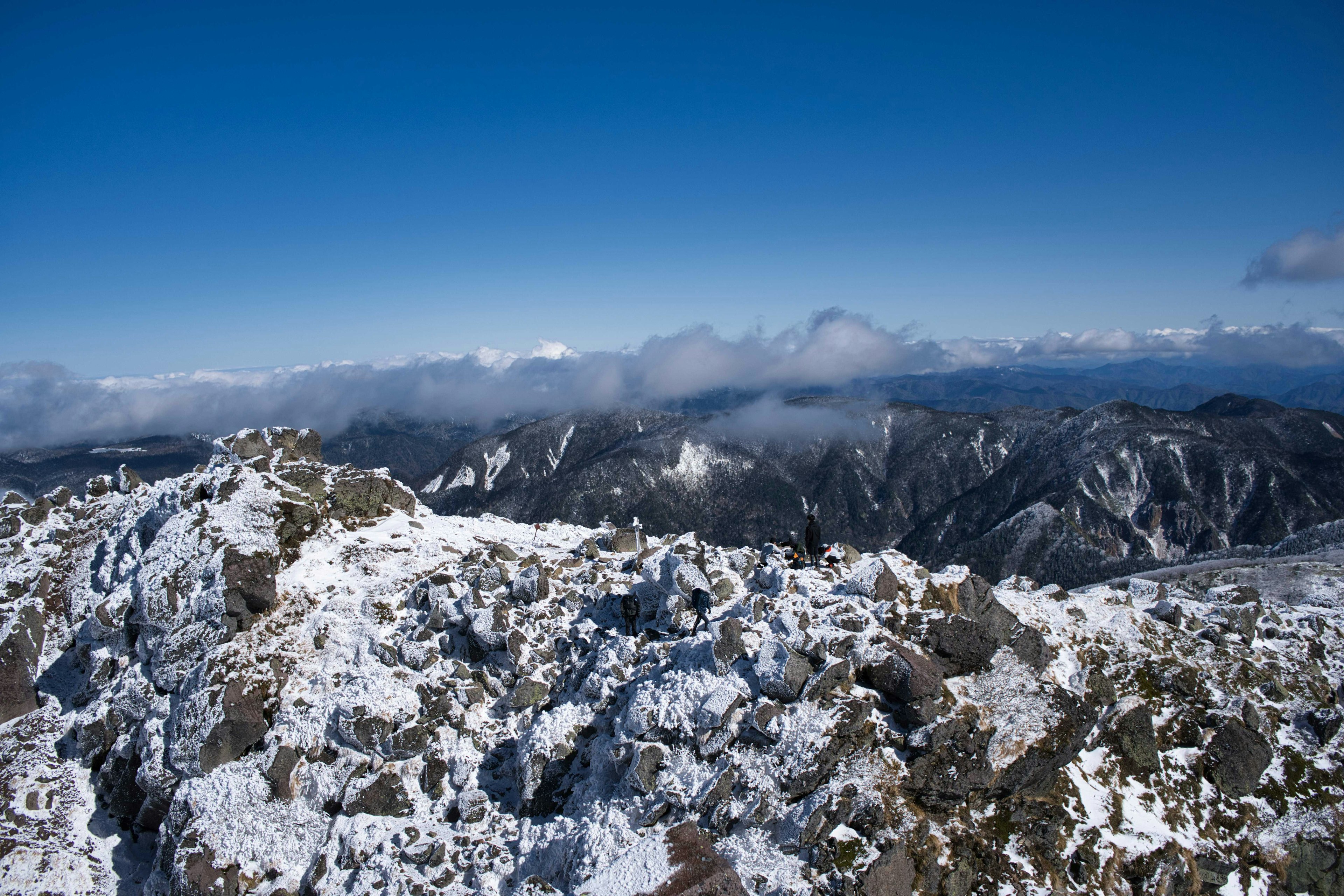 View from a snowy mountain peak with clear blue sky and distant clouds