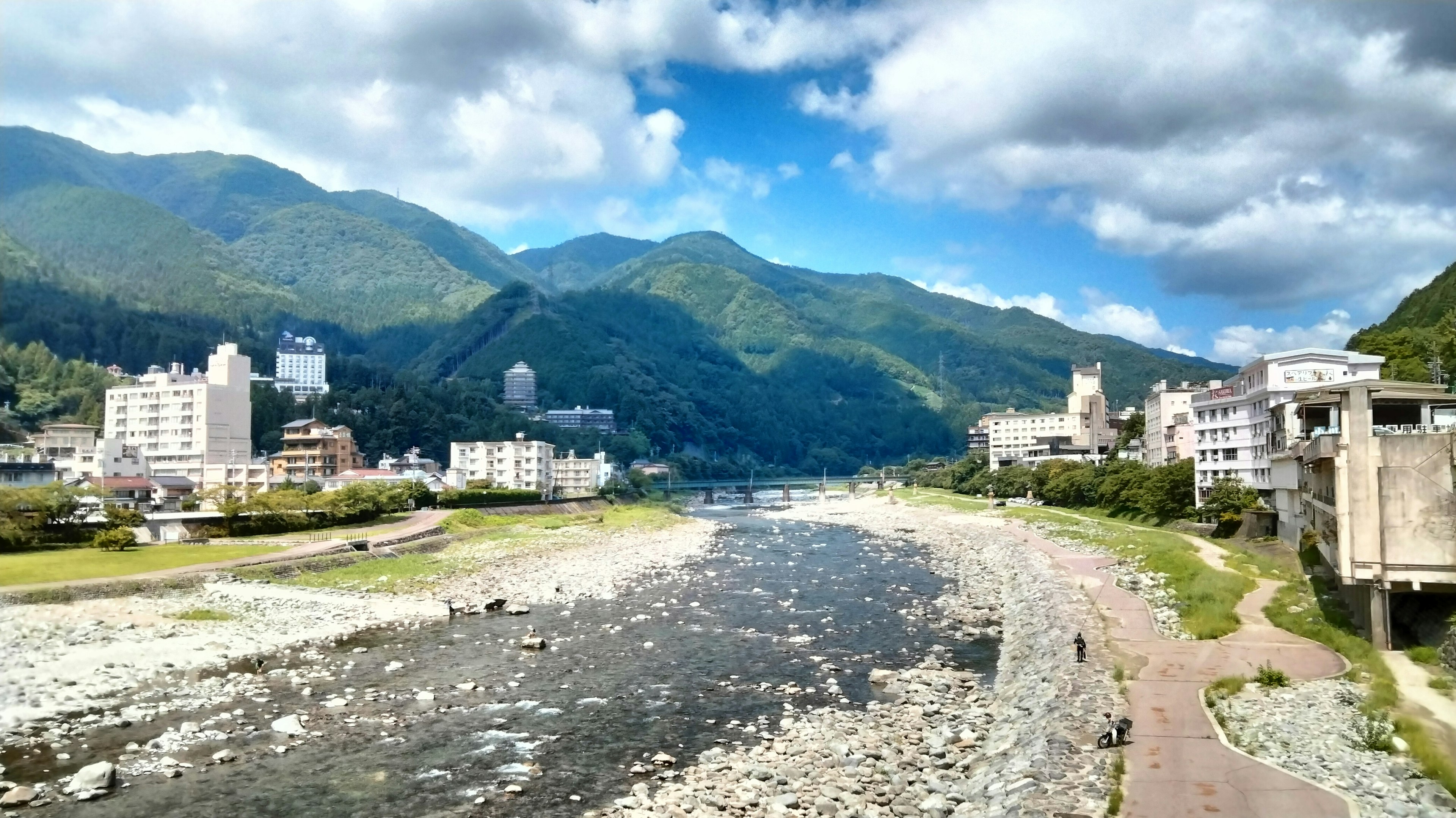 環繞著山脈的河流景觀，岸邊有建築物