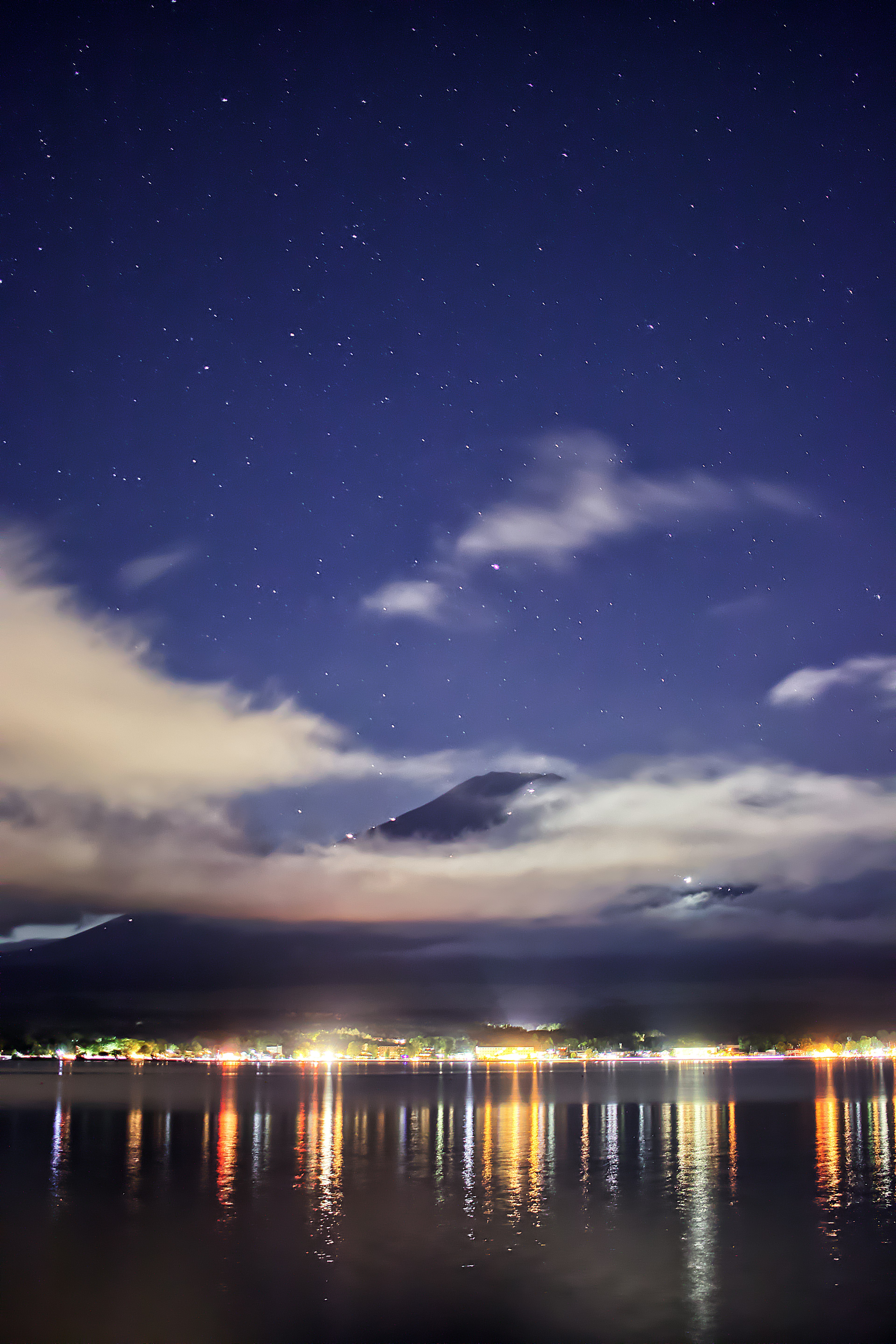 Vista notturna di un lago con stelle e nuvole