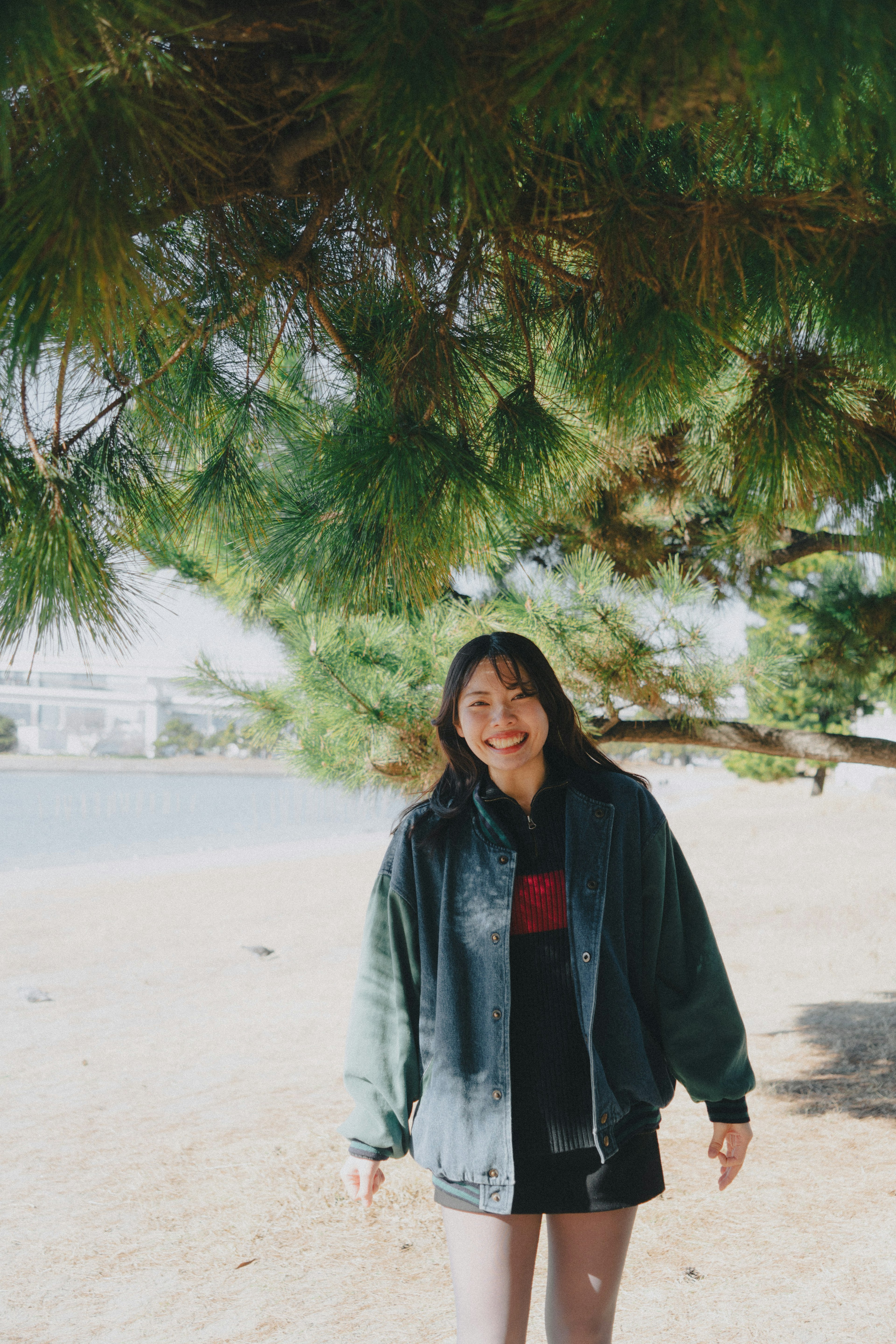 Una donna sorridente sotto un albero vicino alla spiaggia