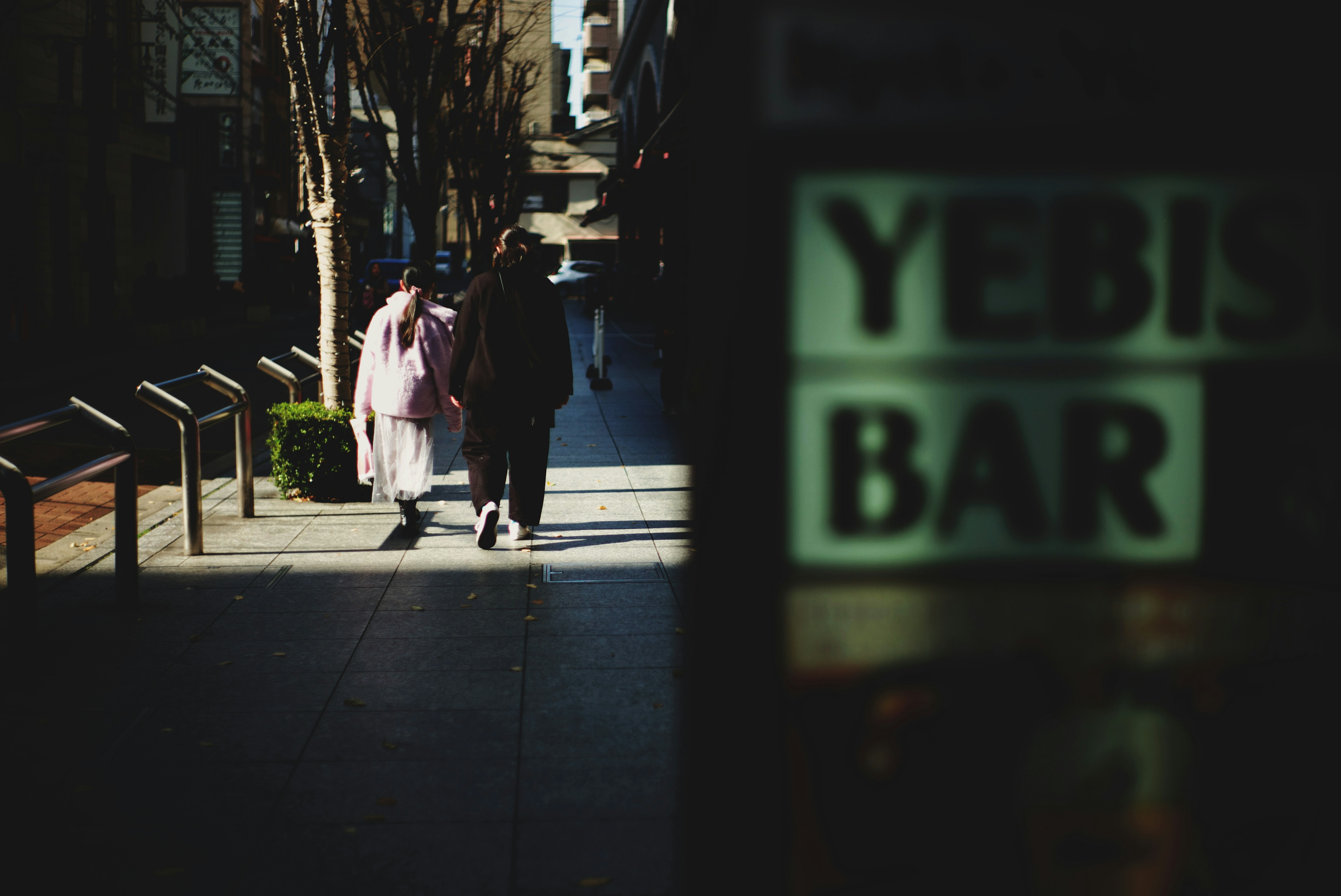 通りを歩く人々と「YEBIS BAR」の看板が見える風景