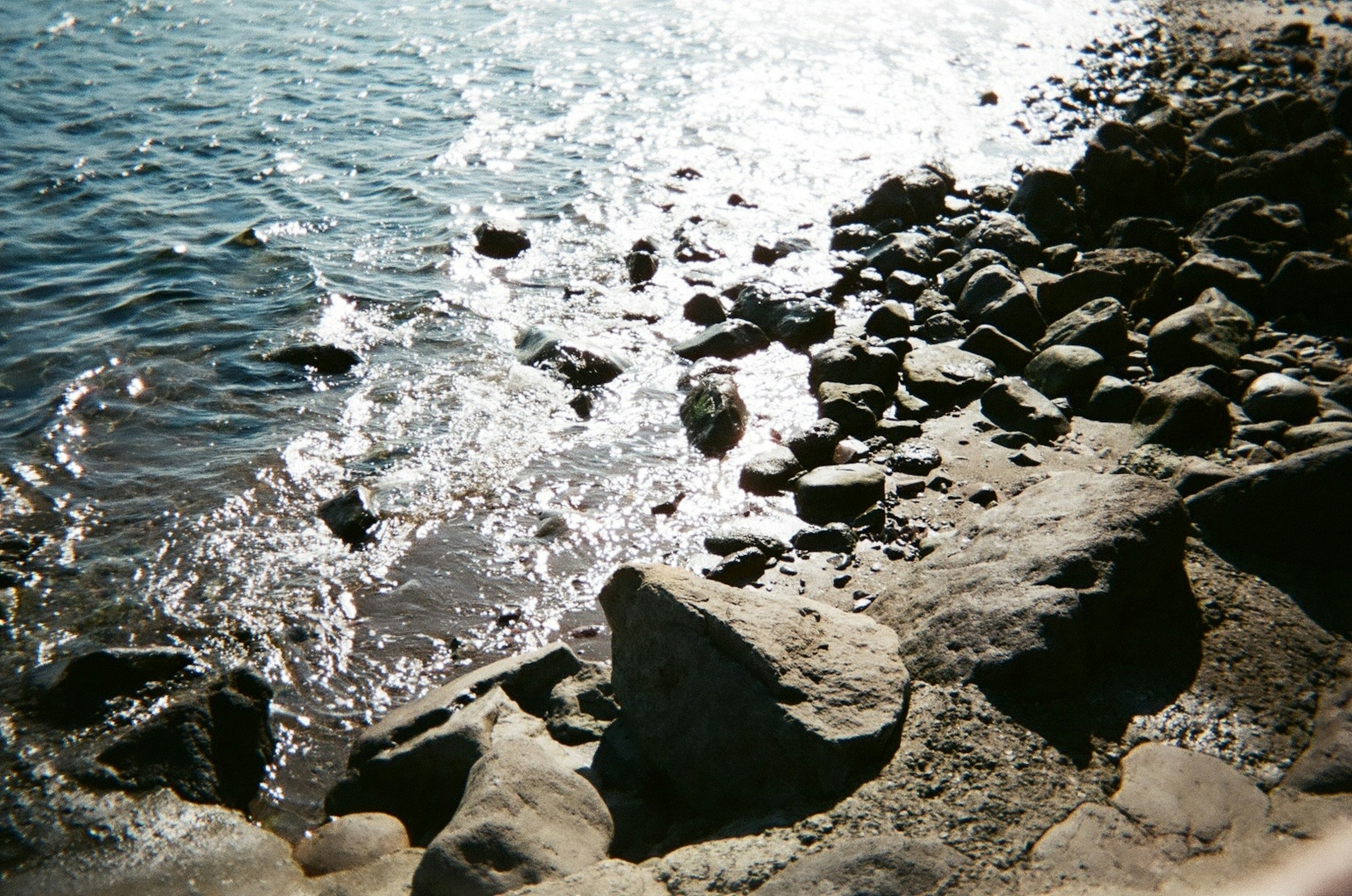 Coastal scene featuring rocks and shimmering water