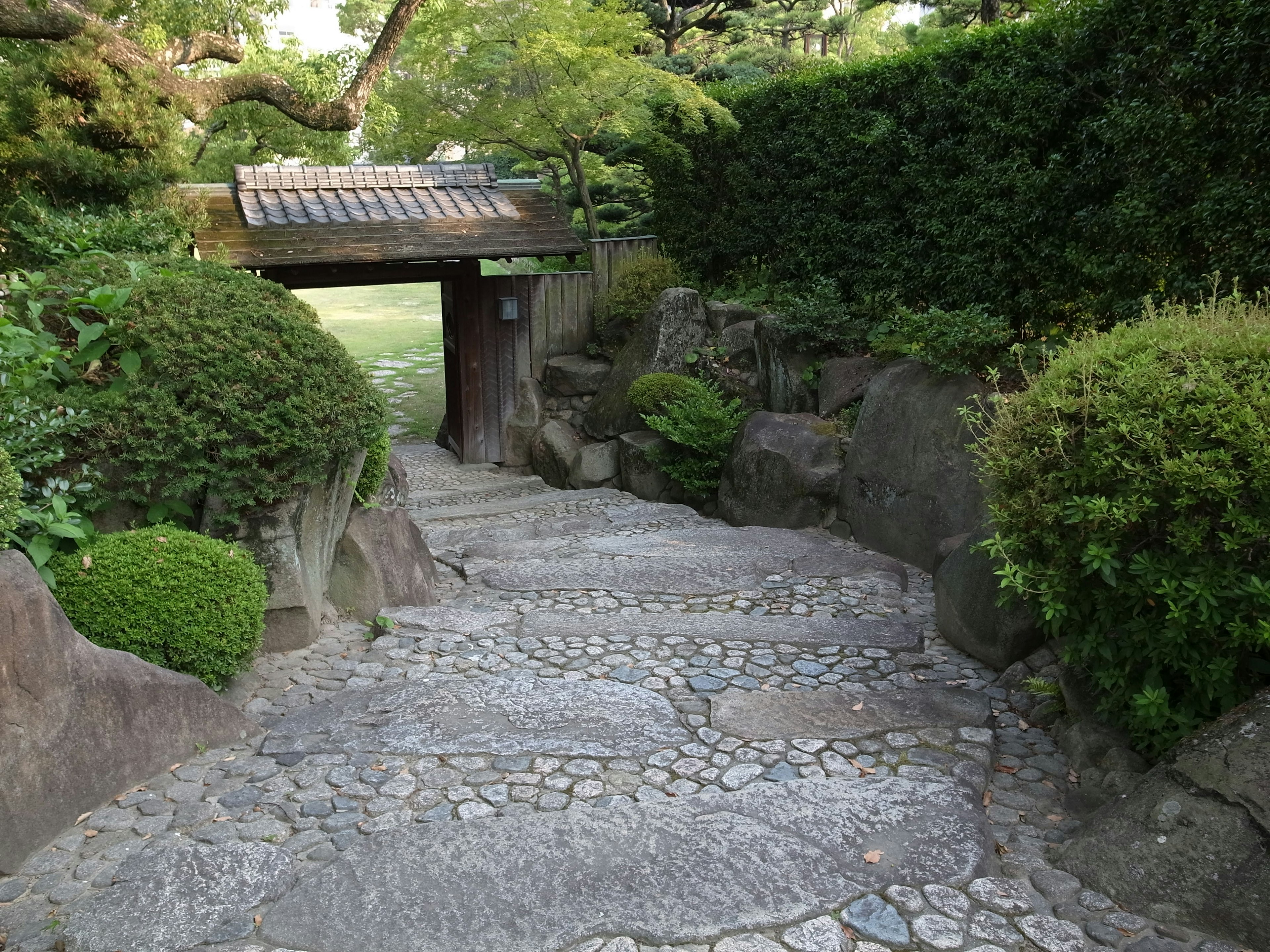 Sentiero in pietra che conduce a un ingresso di giardino sereno circondato da verde lussureggiante