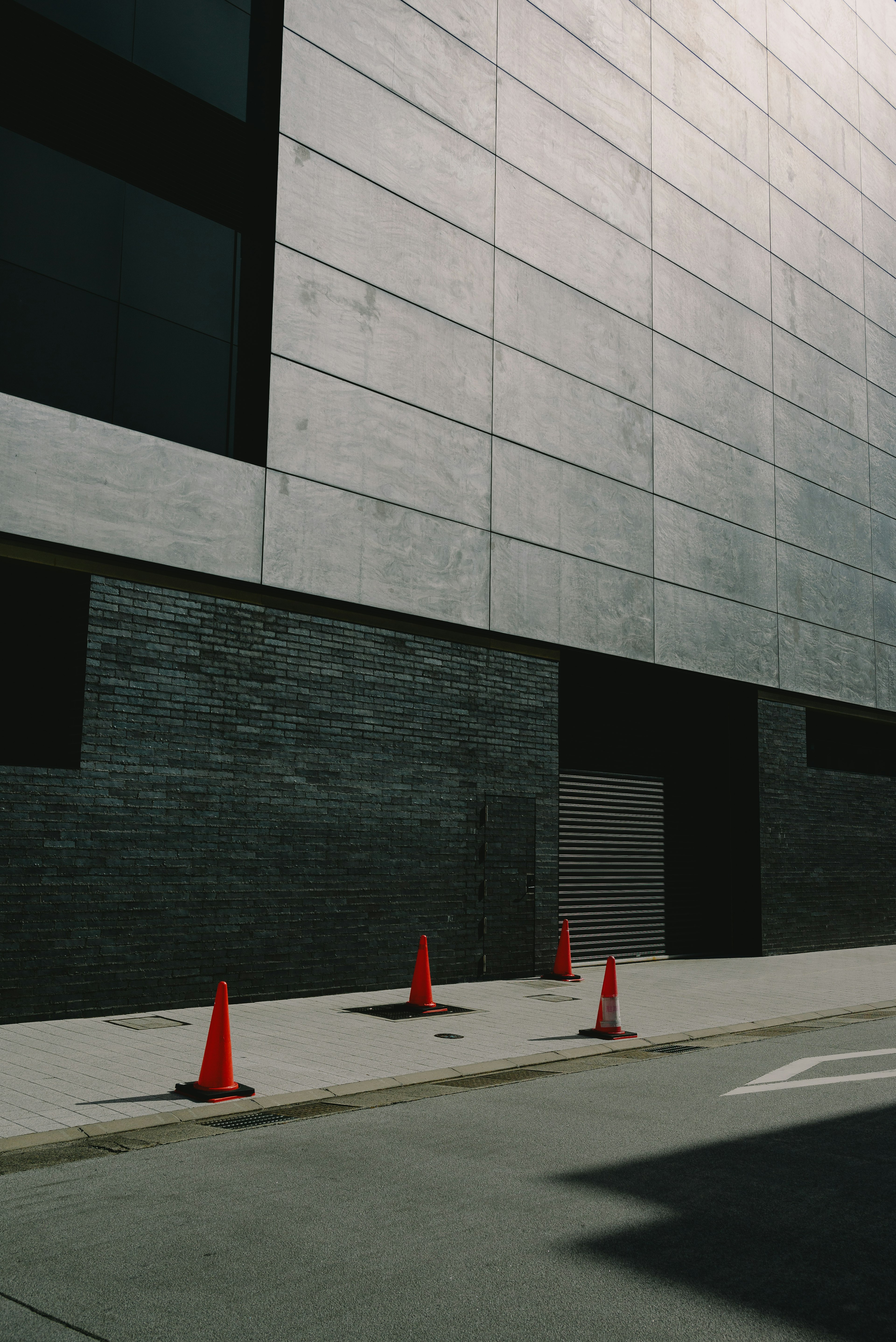 Exterior de un edificio moderno con paredes de concreto y conos de tráfico naranjas