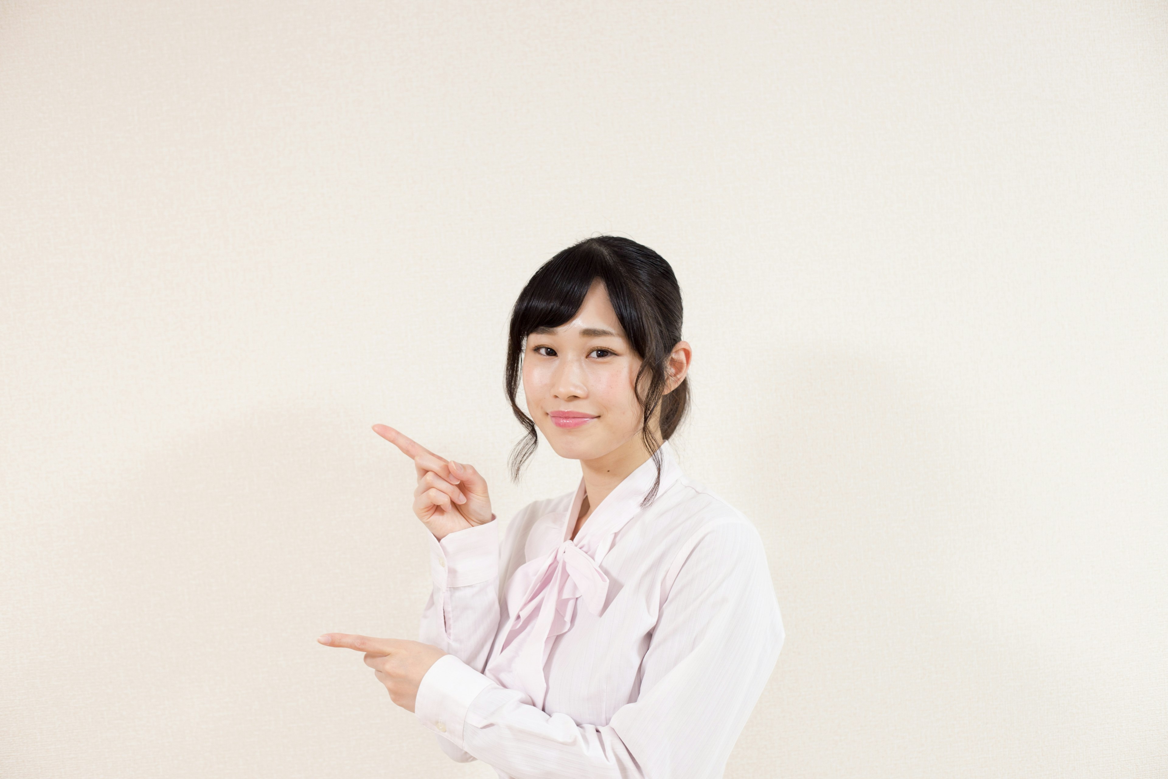 Woman pointing with a smile in front of a white background