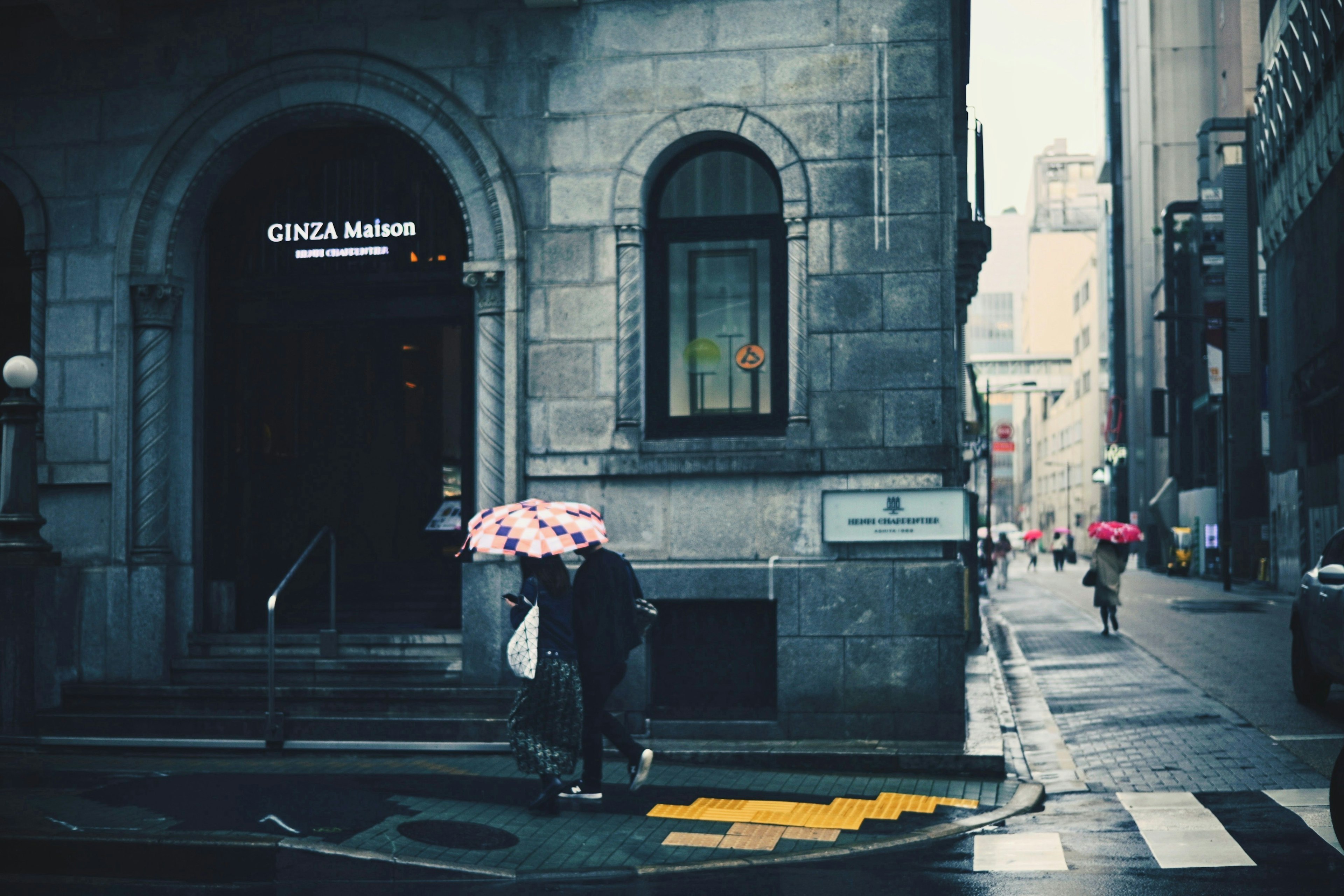 Des gens marchant avec des parapluies sous la pluie près d'un bâtiment historique