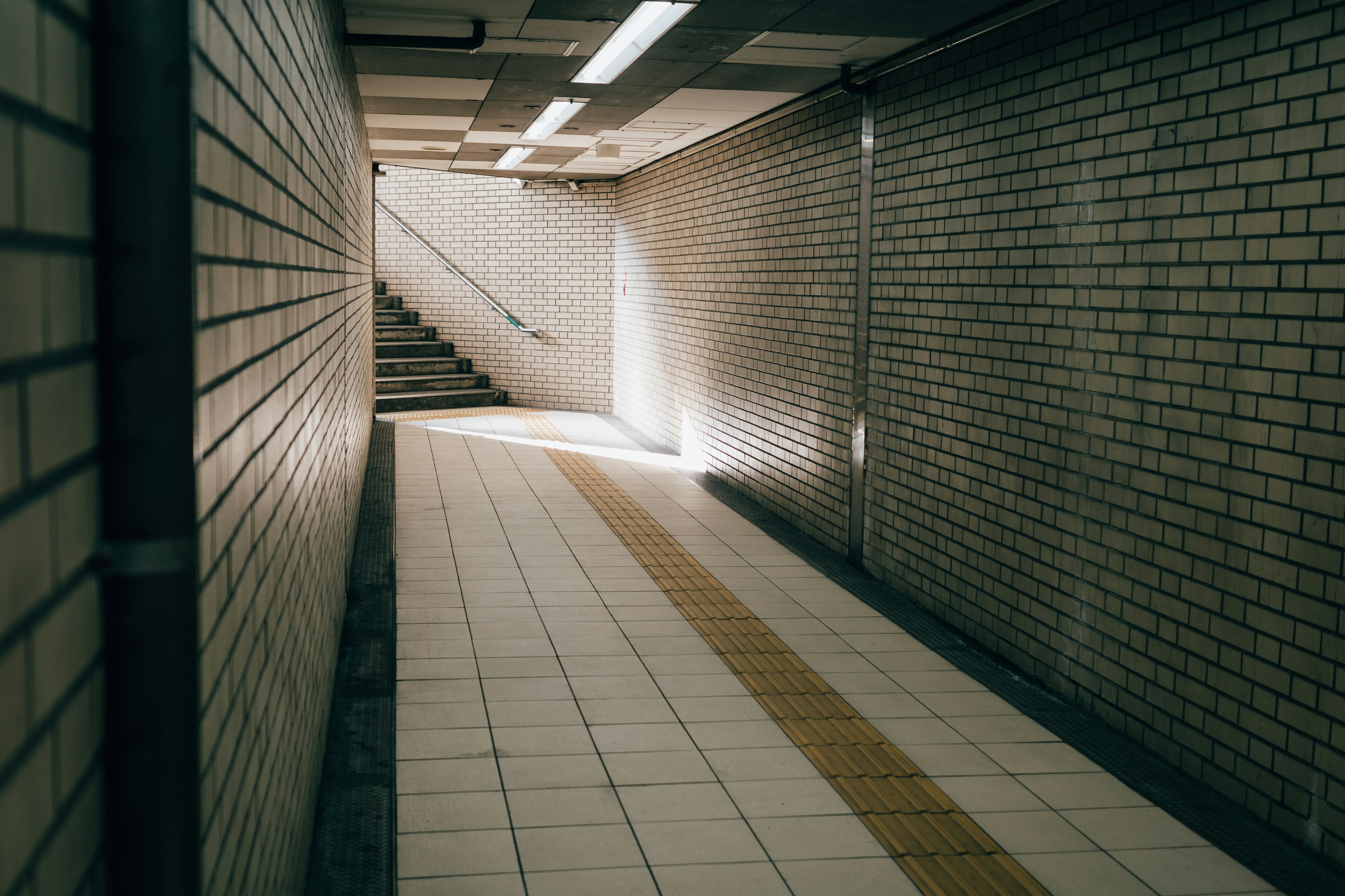 Imagen de un pasaje subterráneo bien iluminado con paredes de azulejos y una escalera