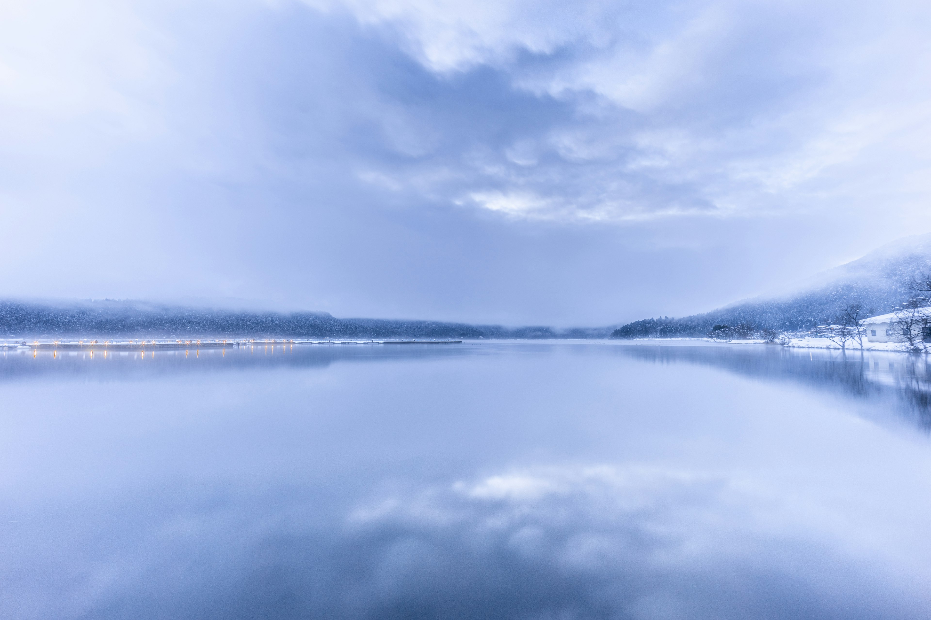 Paesaggio lacustre sereno con tonalità blu che riflettono le nuvole sulla superficie dell'acqua