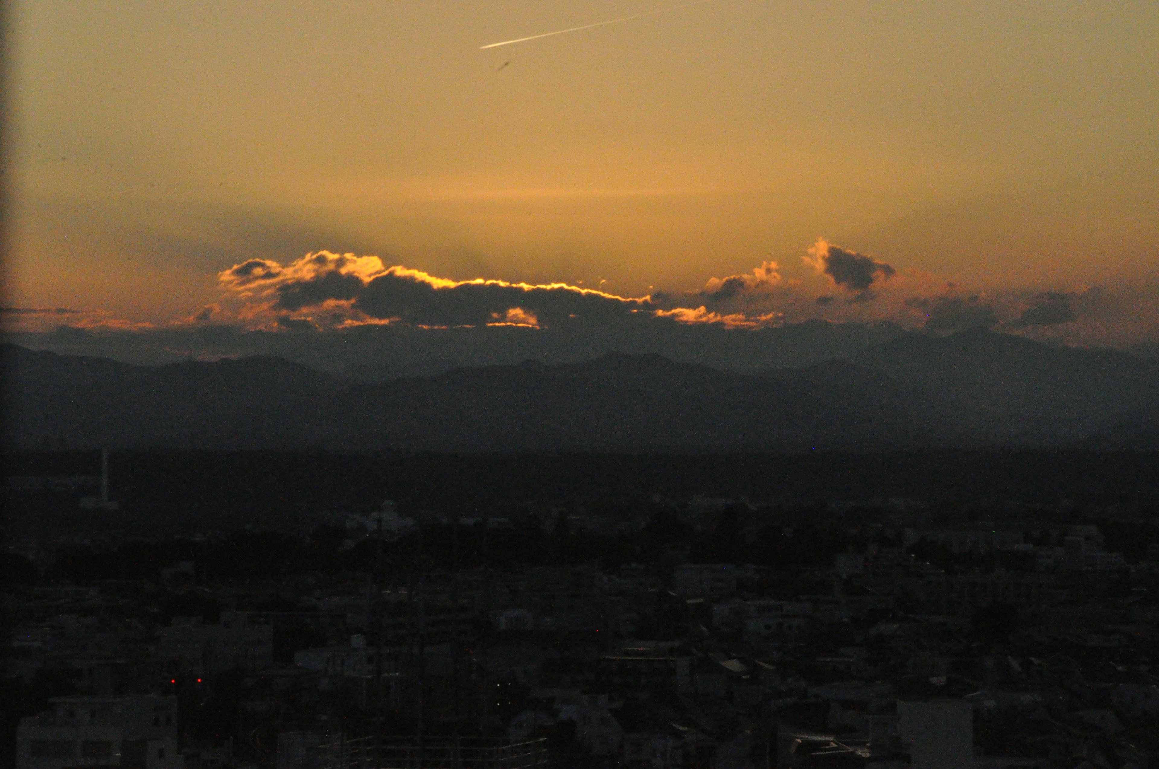 Silhouette von Wolken vor einem Sonnenuntergangshimmel mit Bergen im Hintergrund