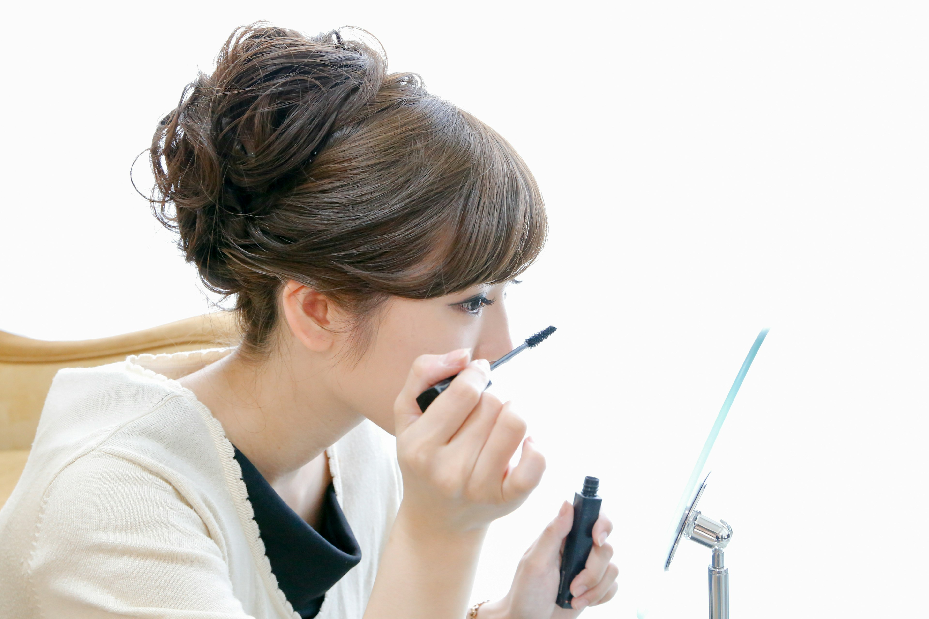 A woman applying eye makeup in front of a mirror