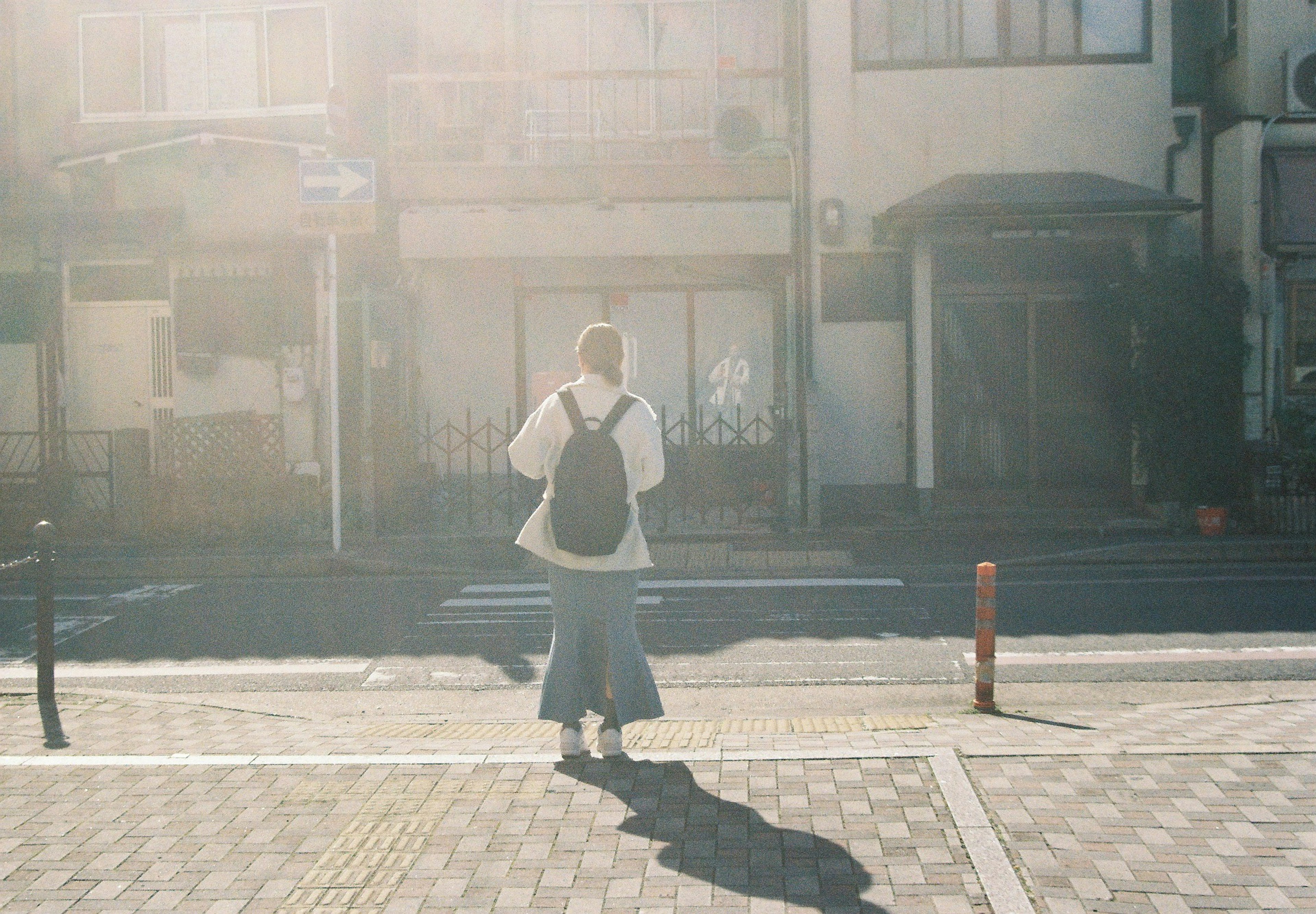 A woman walking away in sunlight on a city street