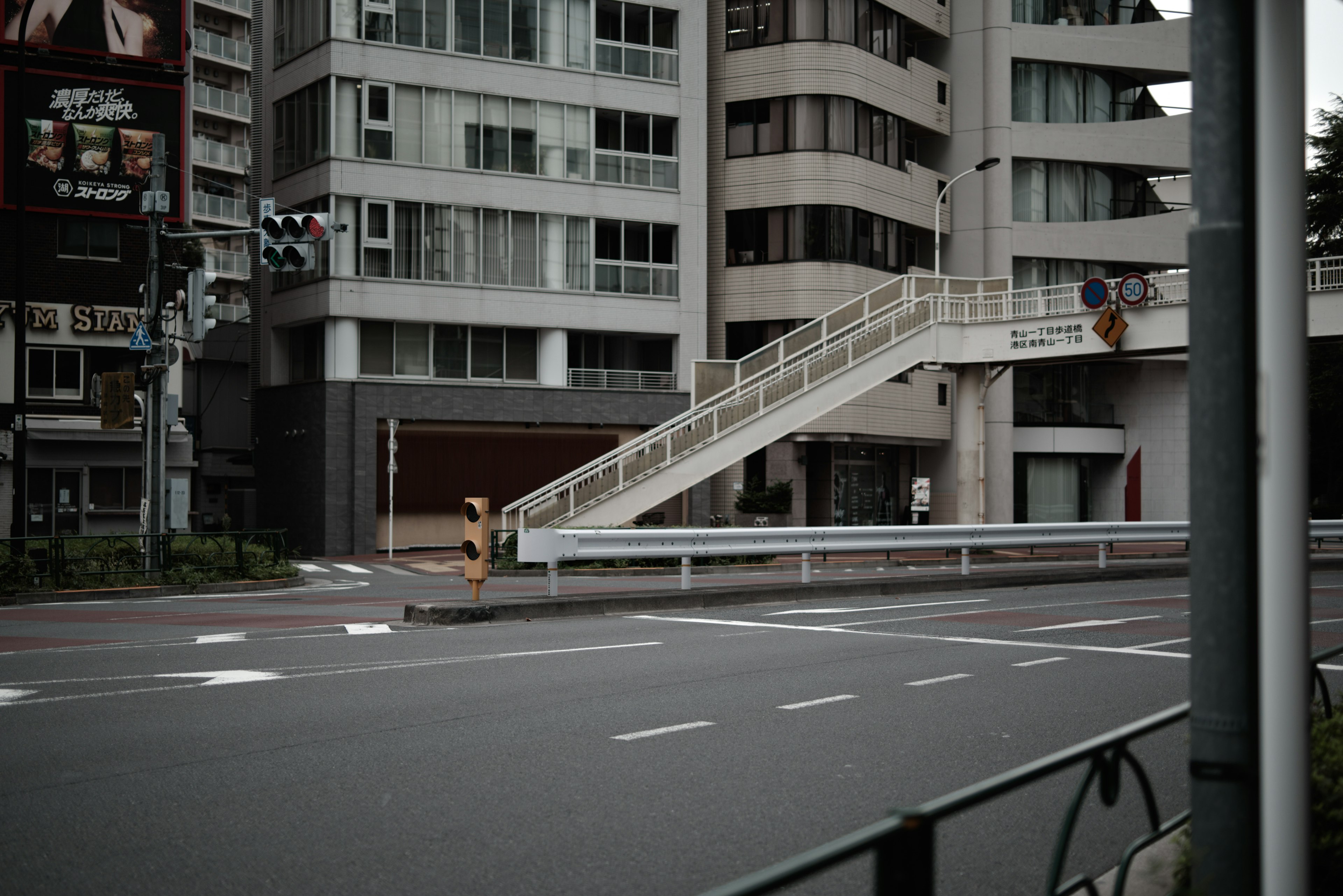 Quiet urban scene featuring tall buildings and a pedestrian overpass