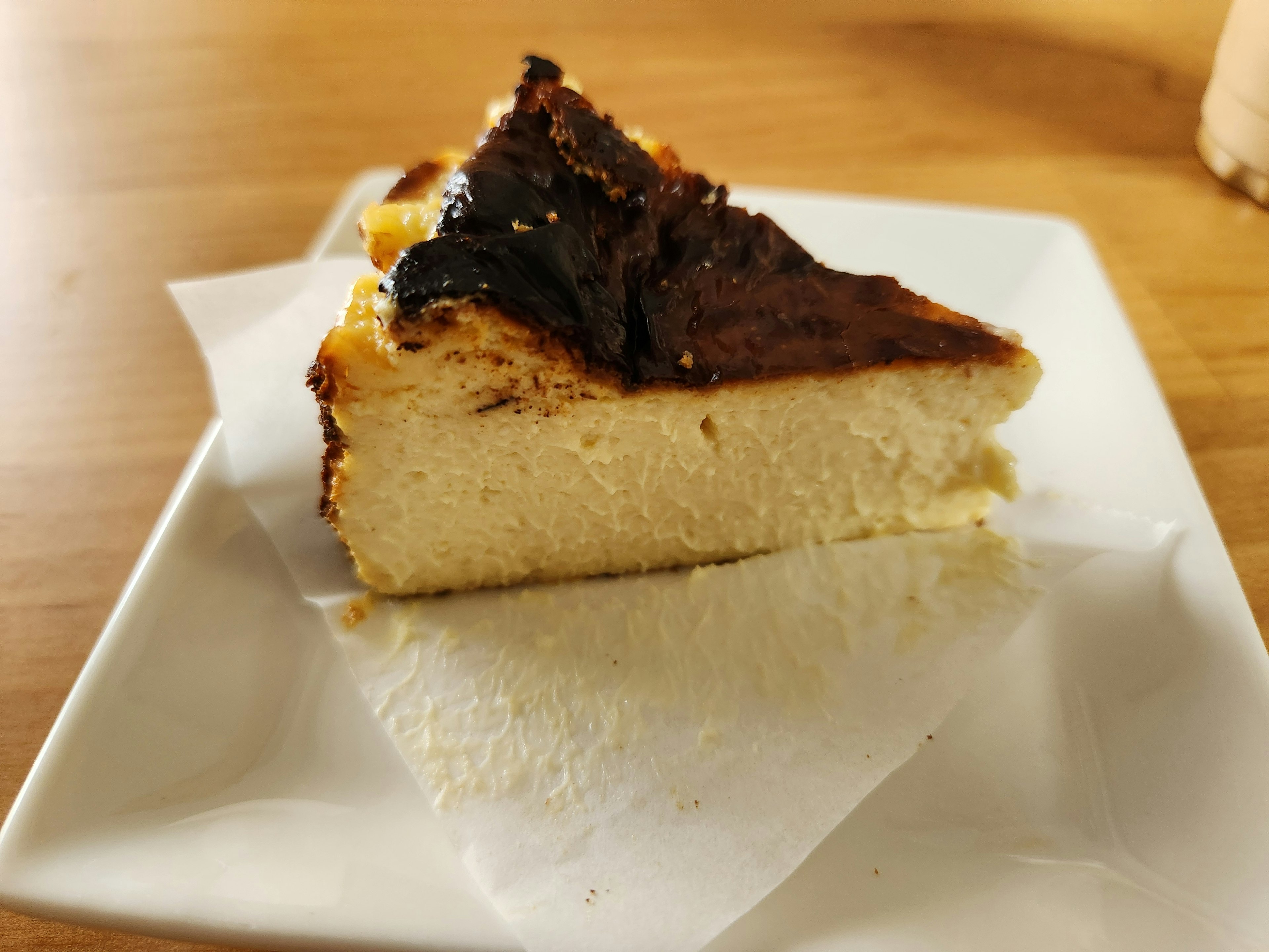 Slice of cheesecake with a caramelized top served on a white plate