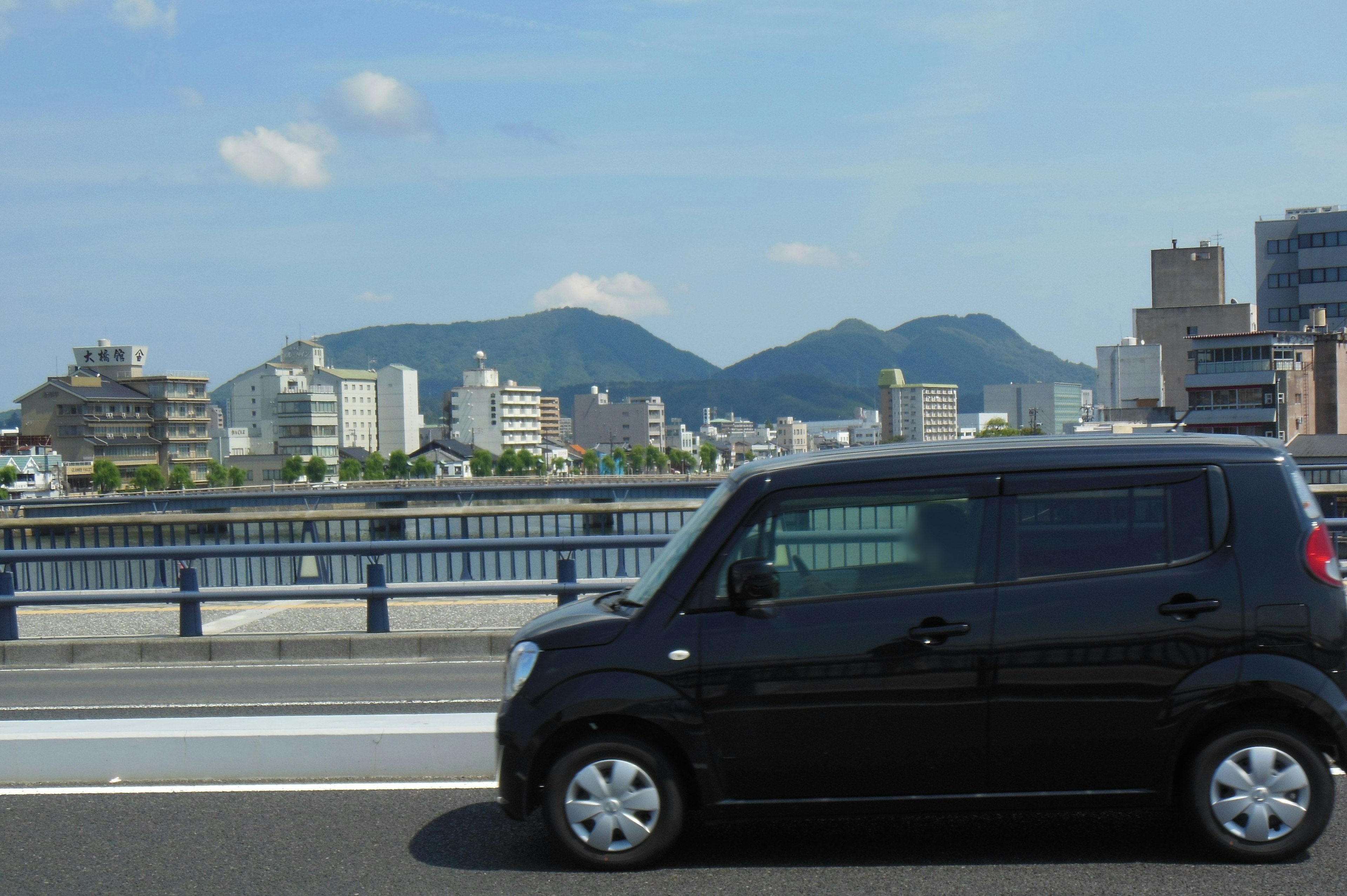 Voiture noire circulant sur une autoroute avec skyline urbain et montagnes