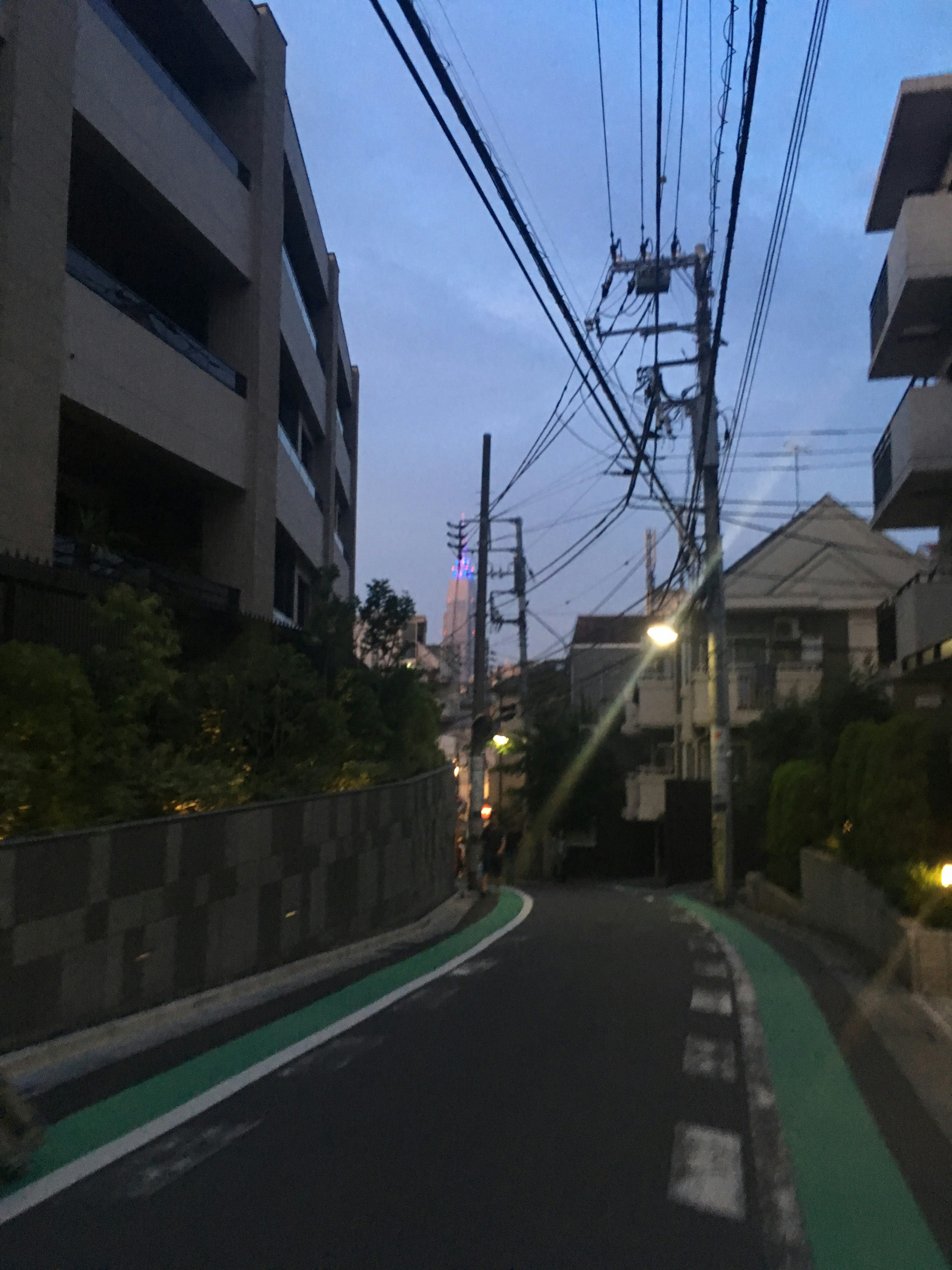 Calle estrecha con edificios y cables eléctricos al anochecer