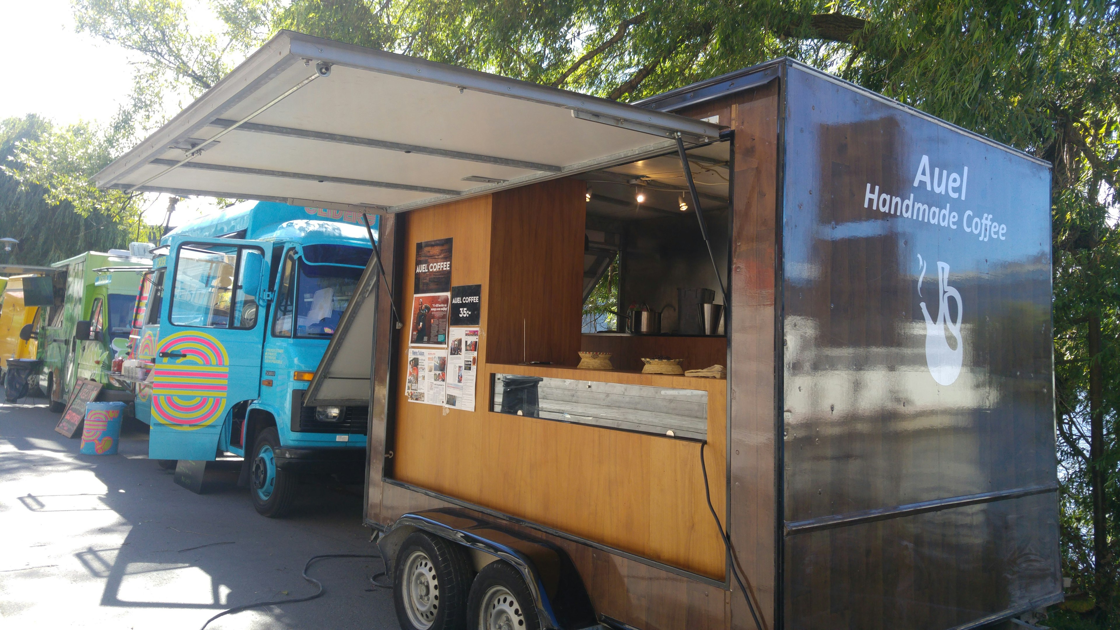 Remorque à café avec extérieur en bois à côté d'un camion de nourriture bleu