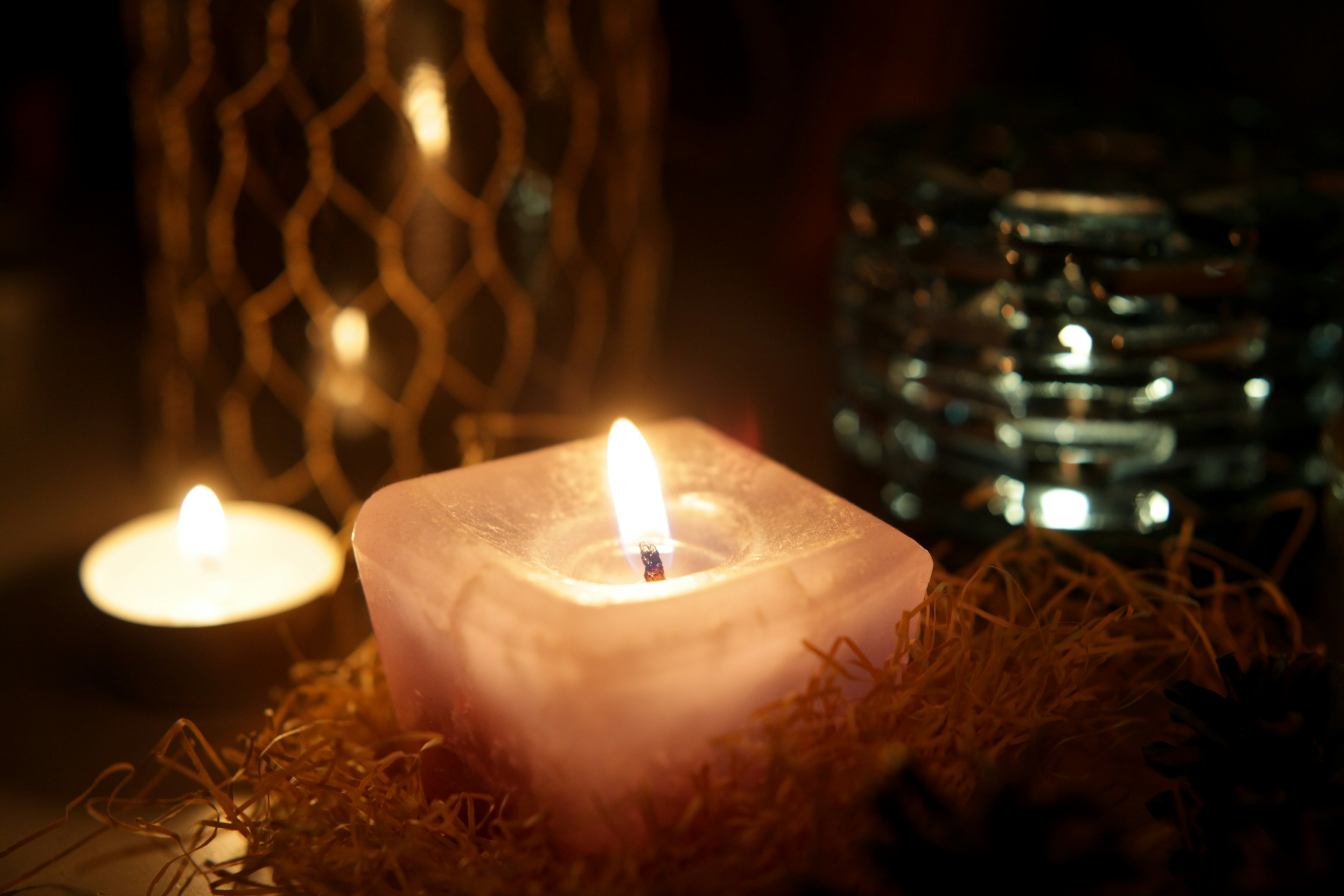 Softly glowing purple candle with decorative candle holders in the background