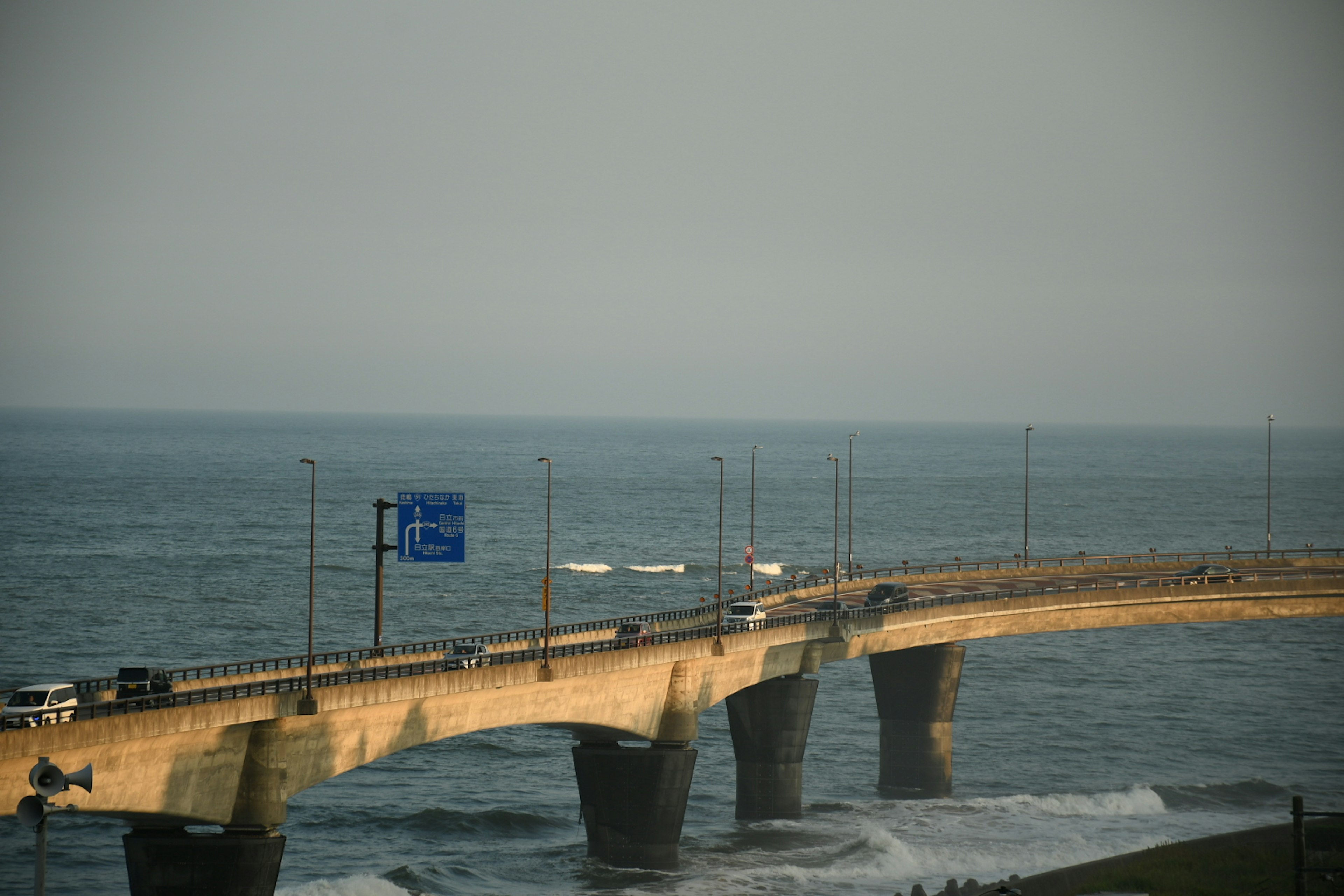 Eine Brücke über das Meer mit Autos und einem blauen Schild