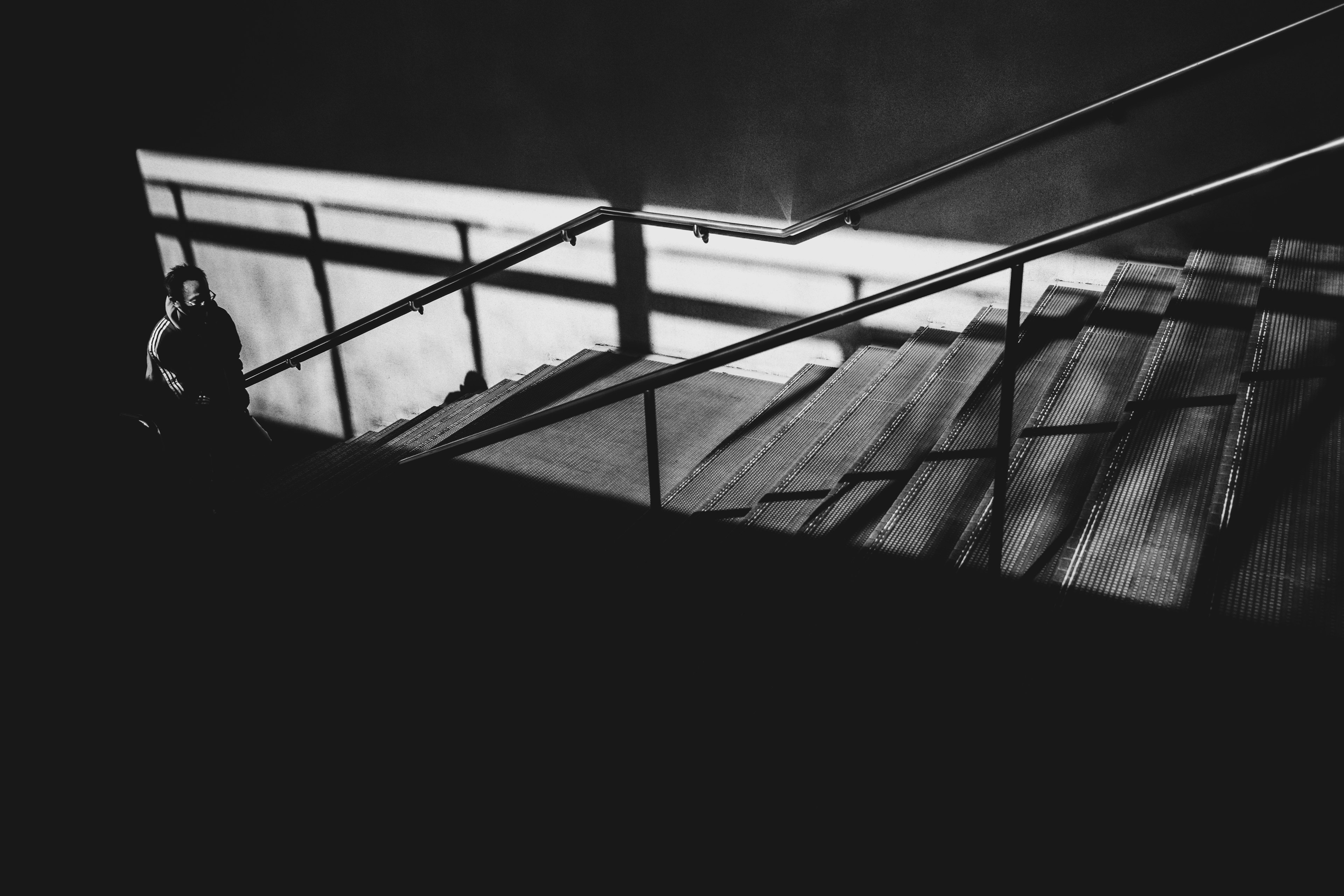 Silhouette of a person against staircase shadows and railing