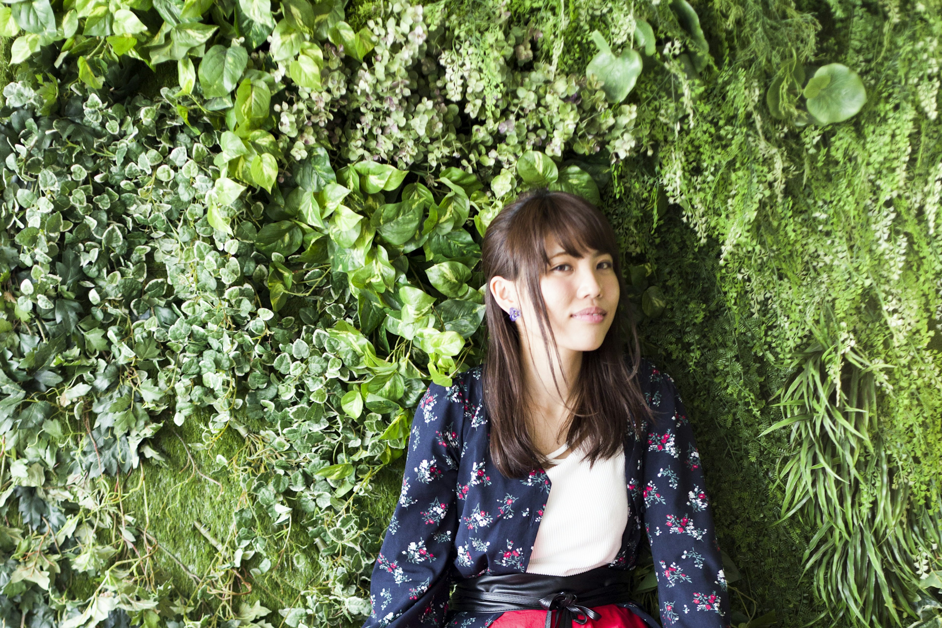 Portrait of a woman sitting in front of a lush green wall