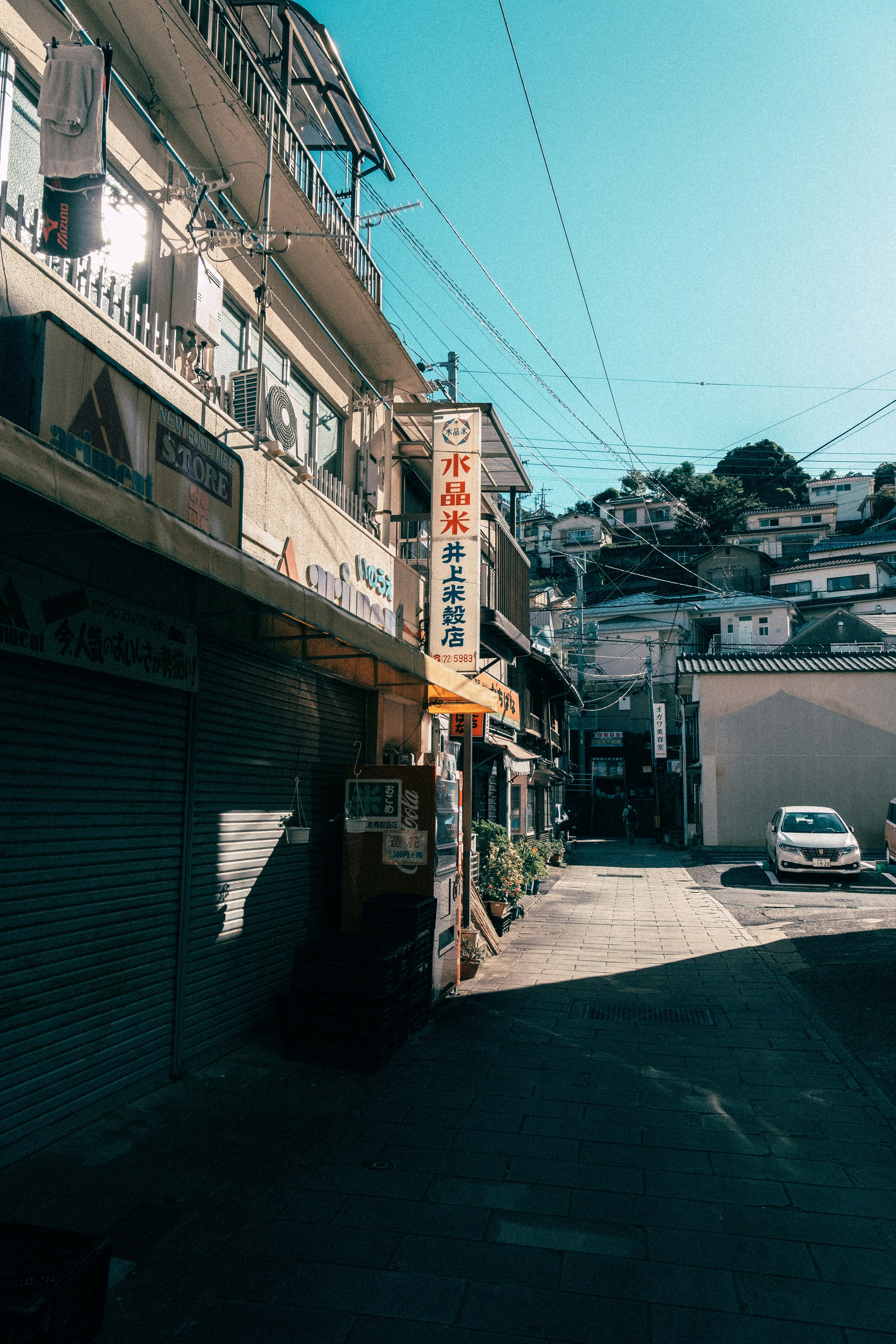 Narrow street view with shops and houses under a clear blue sky