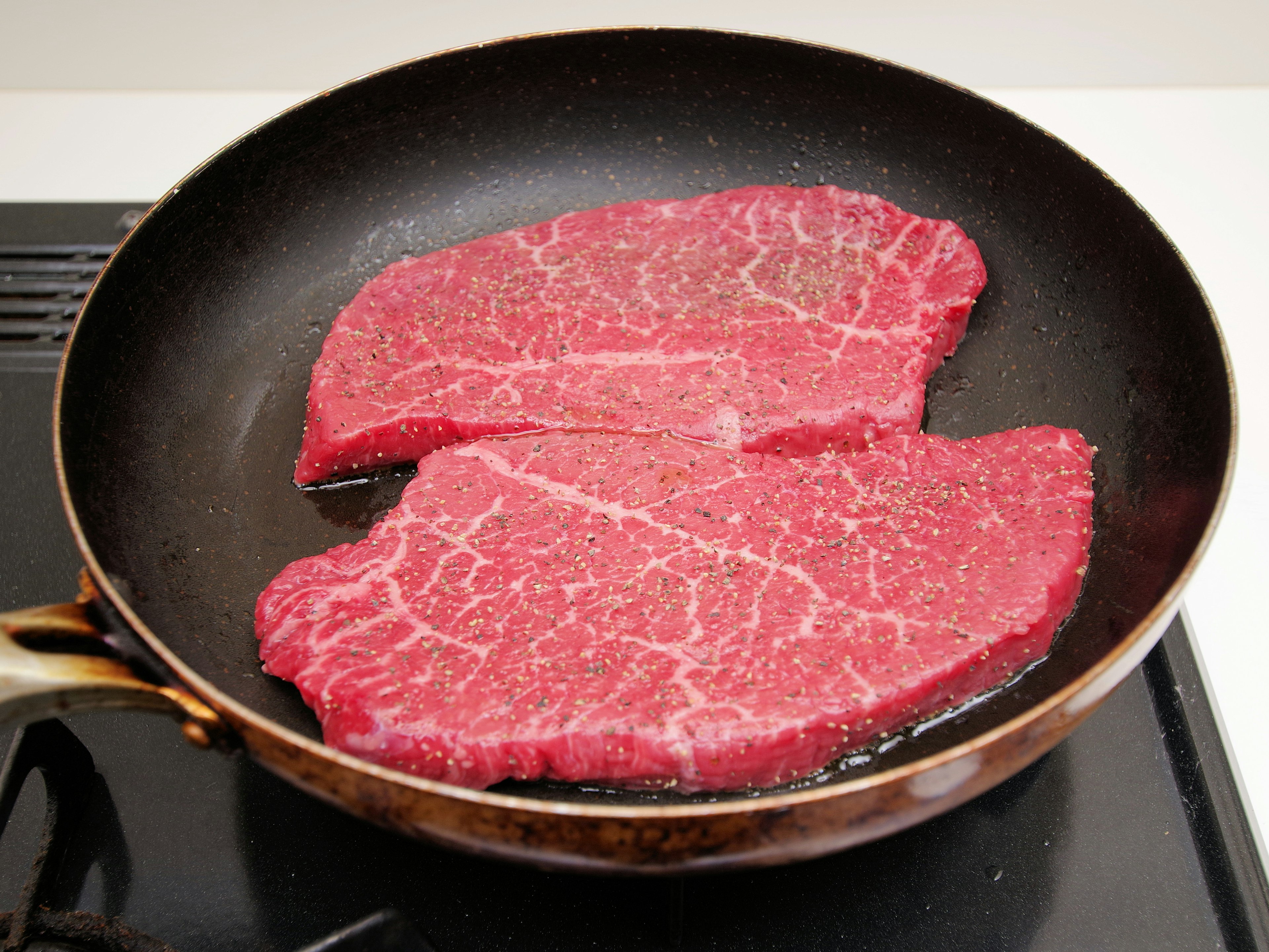 Sliced red meat cooking in a frying pan