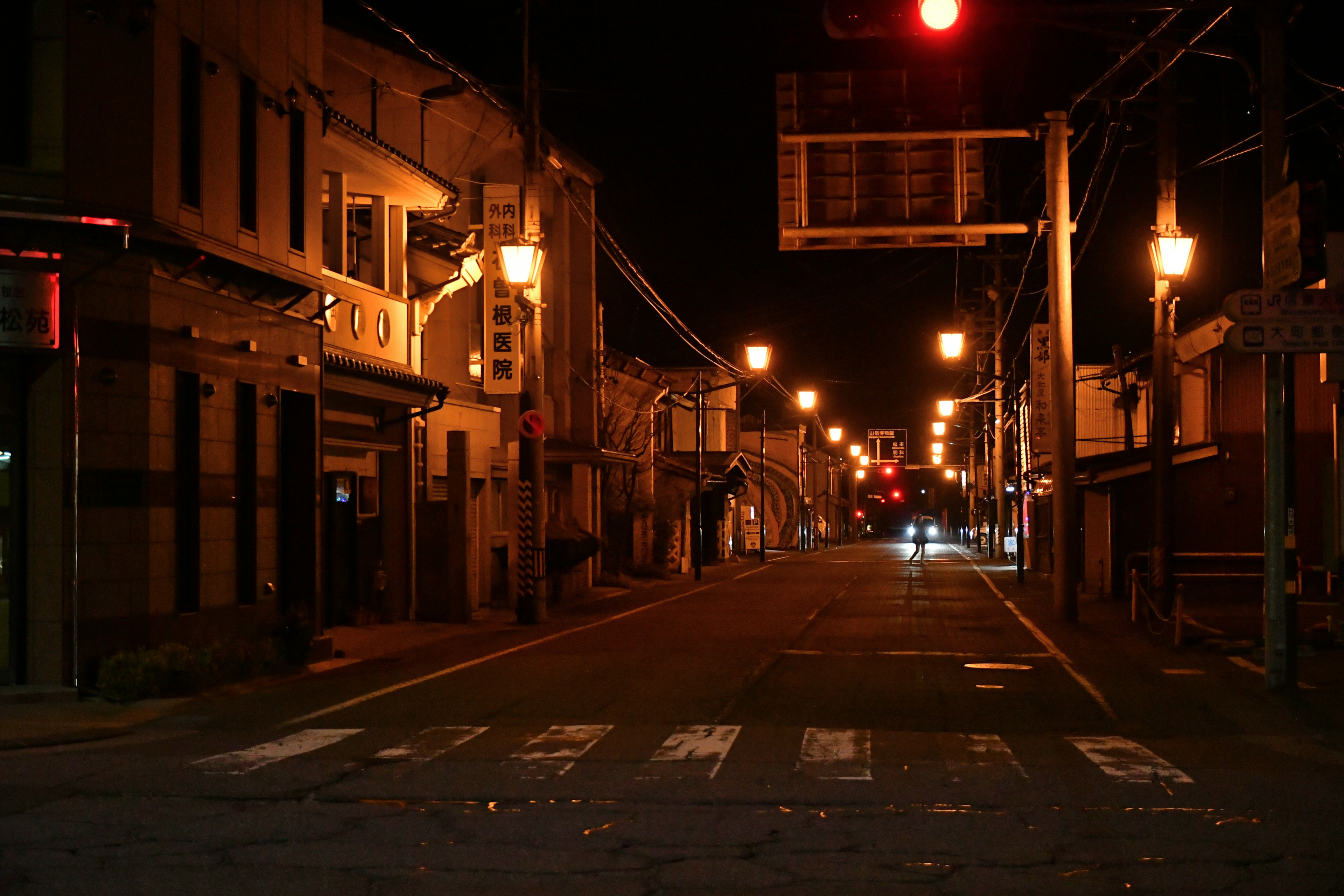 Quiet street at night with red traffic light and illuminated street lamps