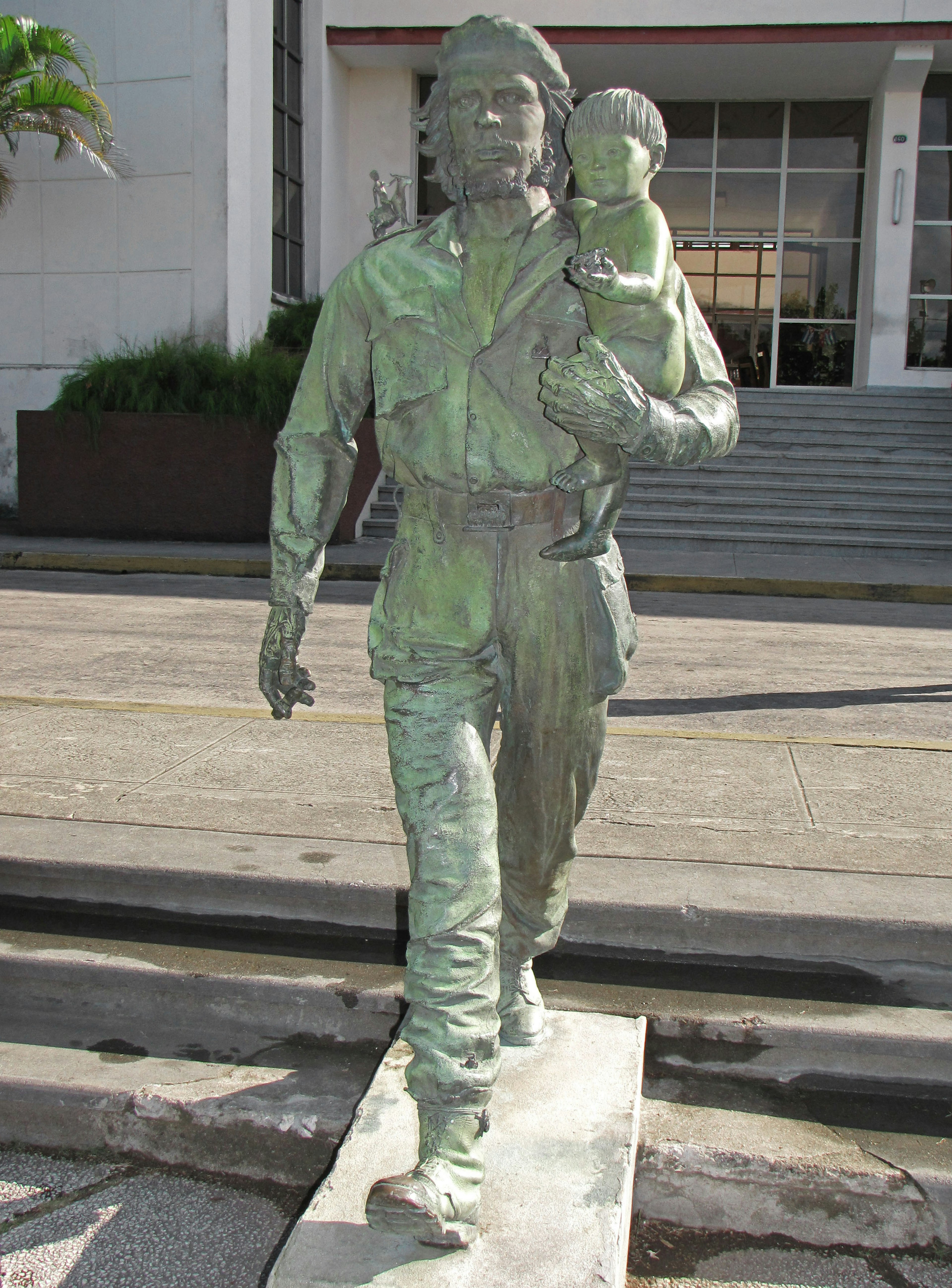 Bronze statue of a man walking while carrying a child