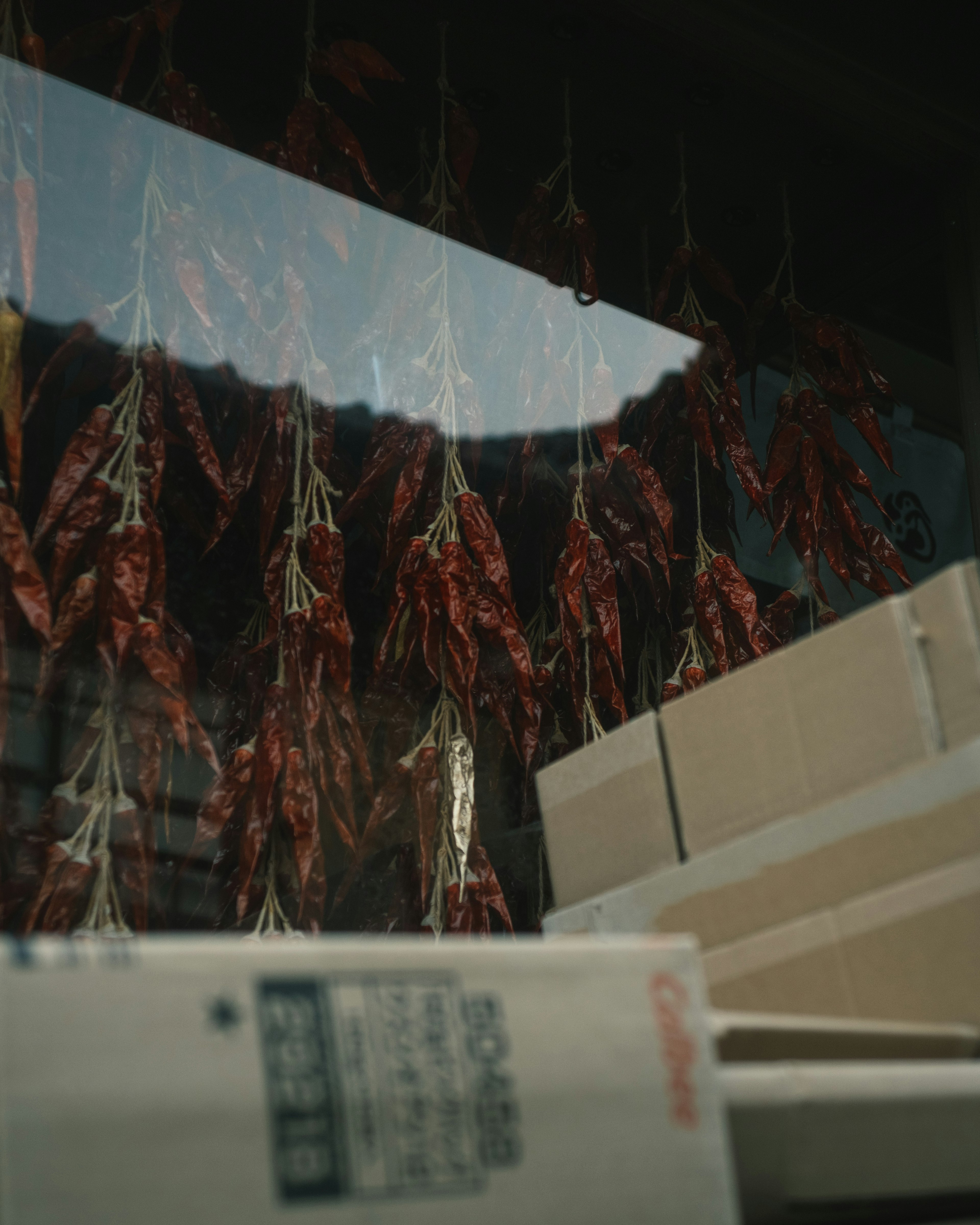 Interior of a shop with dried chili peppers hanging and boxes arranged below