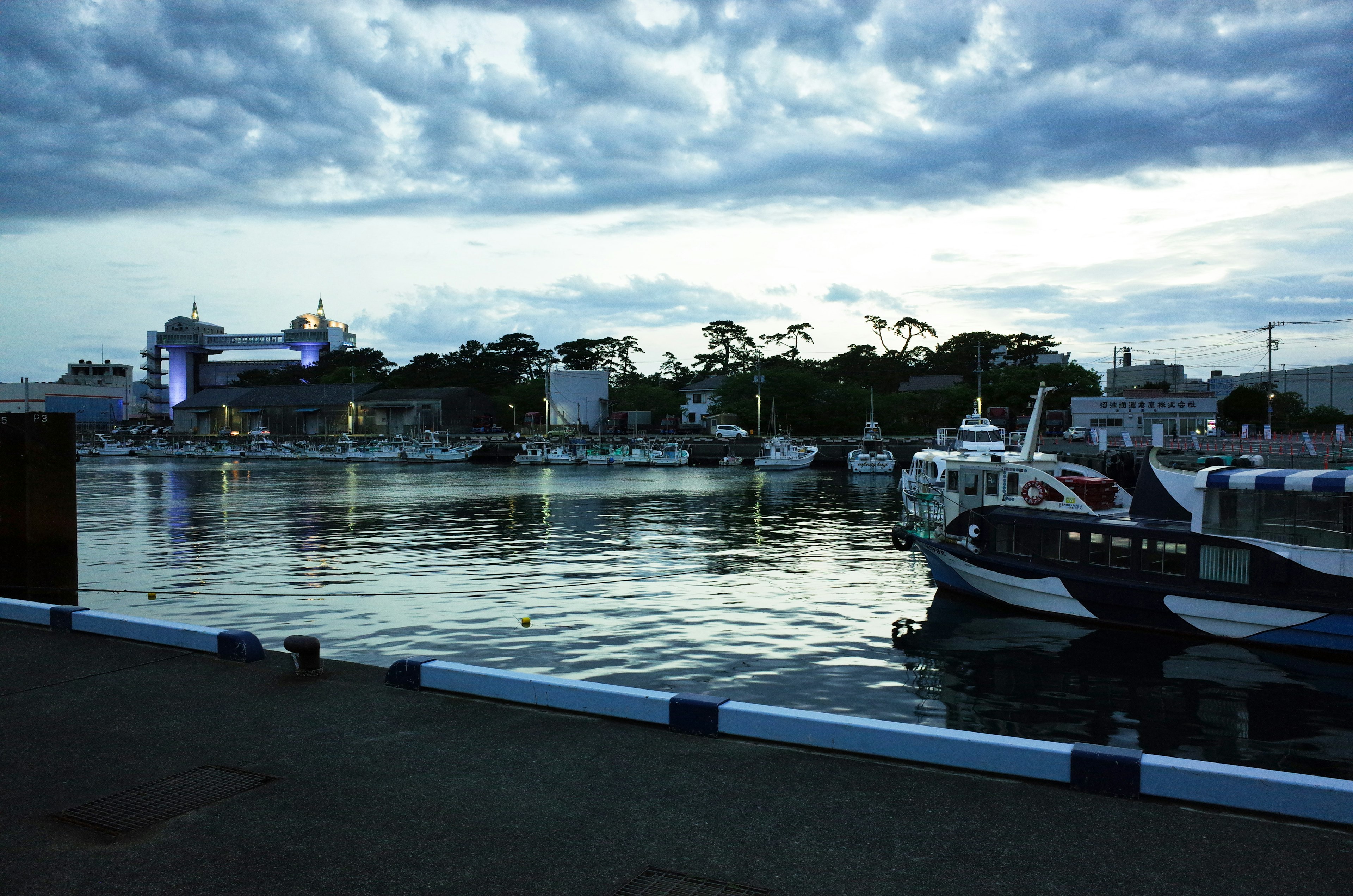 Calm harbor scene with boats floating and clouds reflecting on the tranquil water