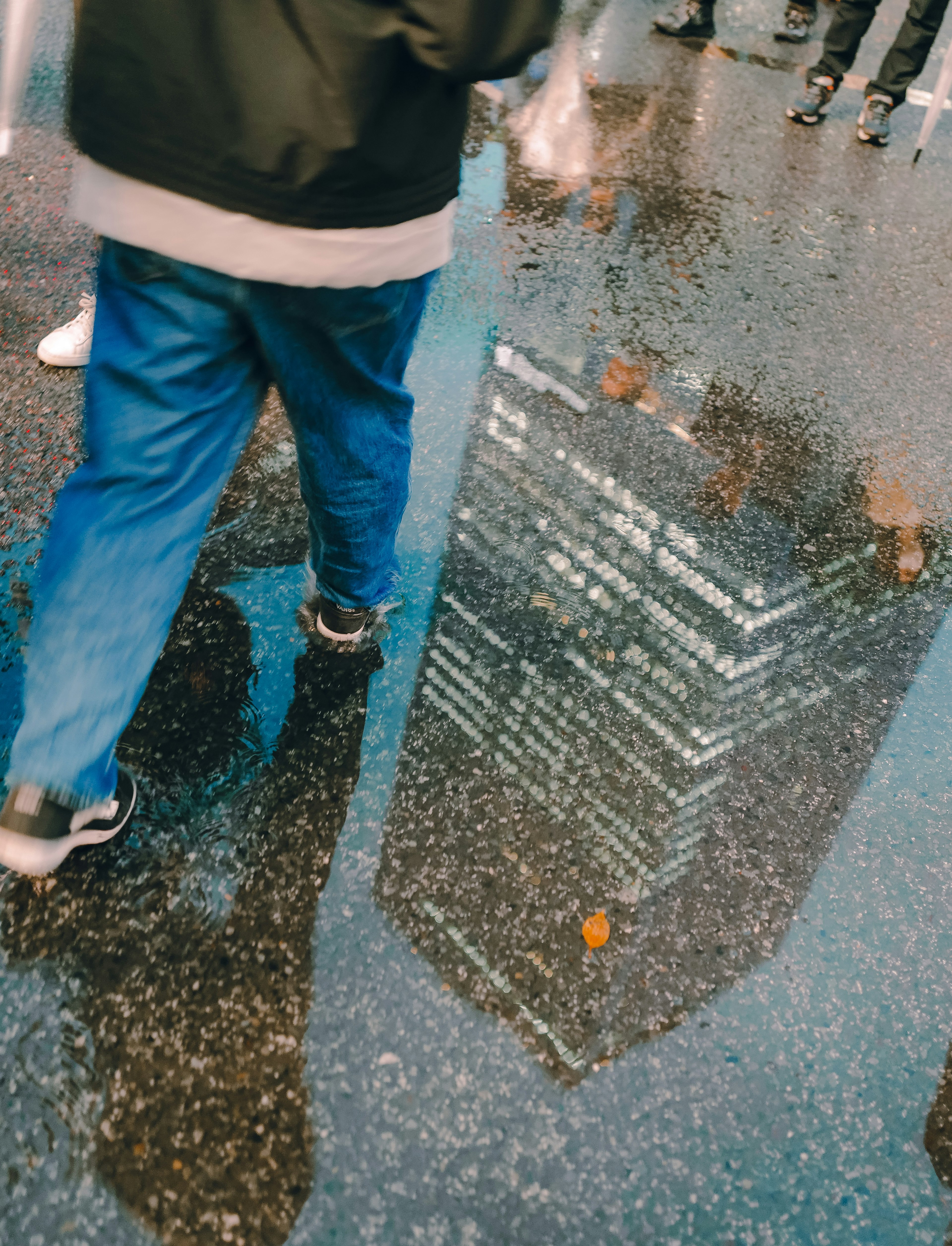 Reflection of people’s feet and a building in a puddle