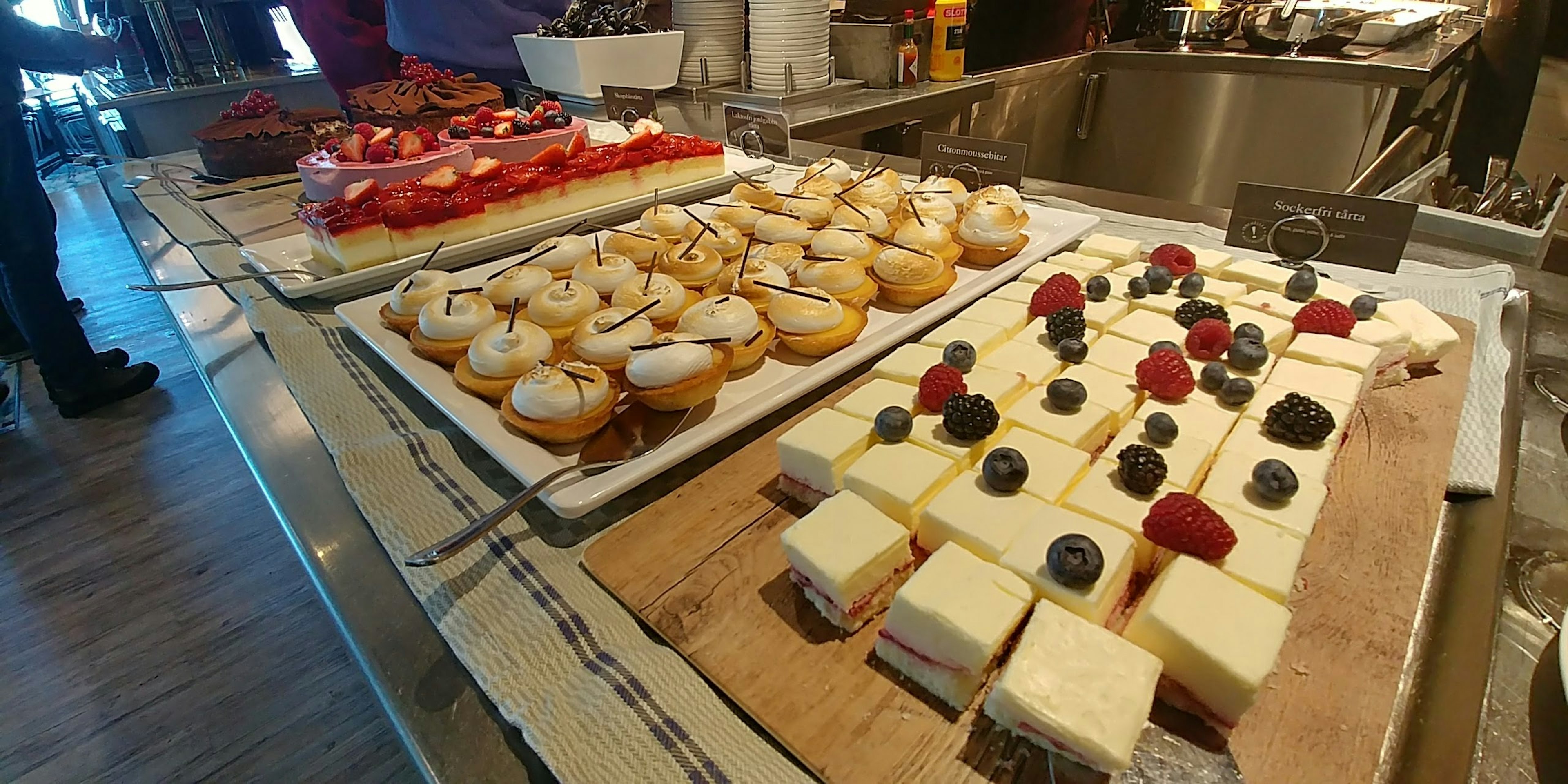 Buffet di dessert con cupcake e crostate di frutta su un tavolo espositivo