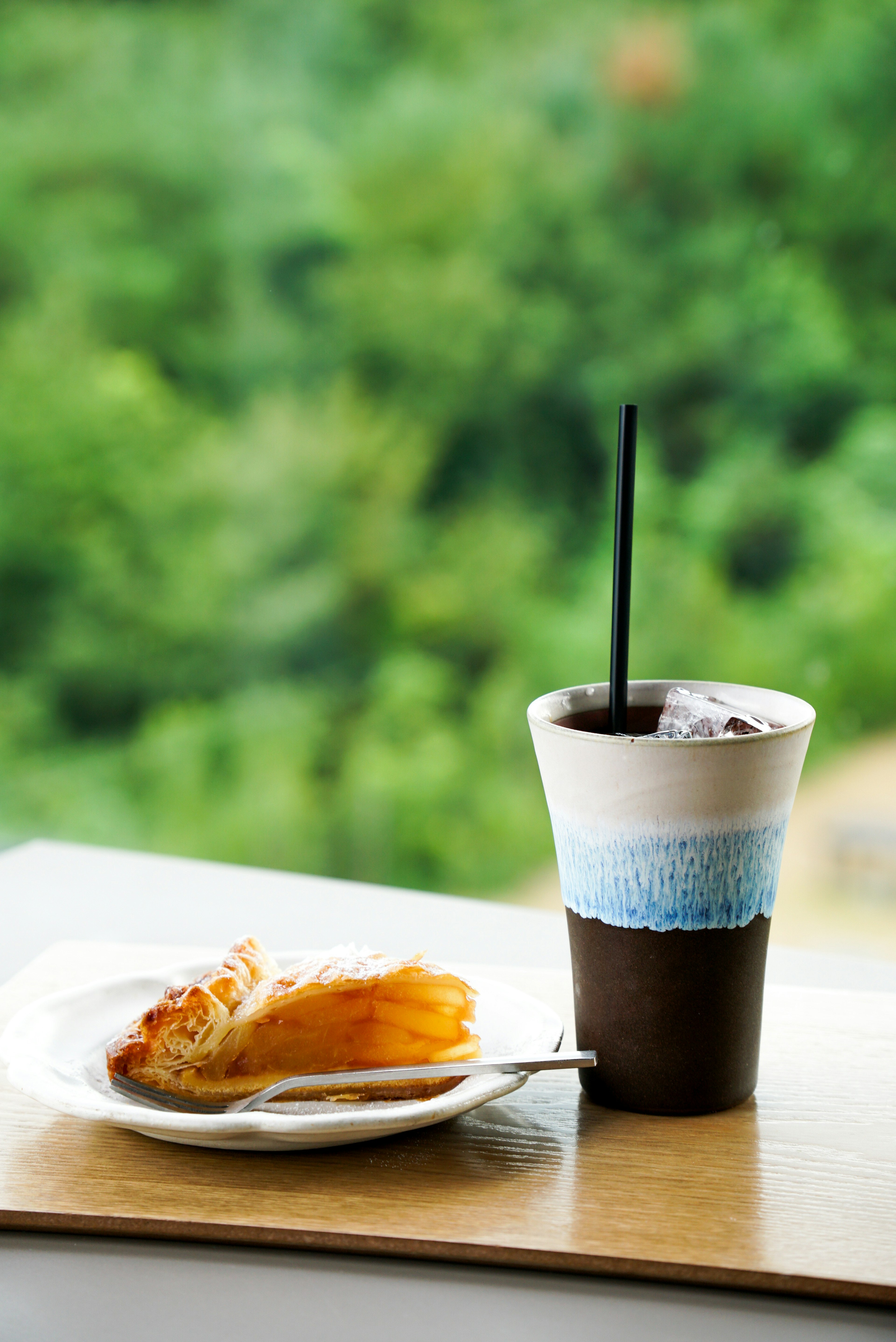 Une simple table avec un café glacé et une part de gâteau sur fond vert