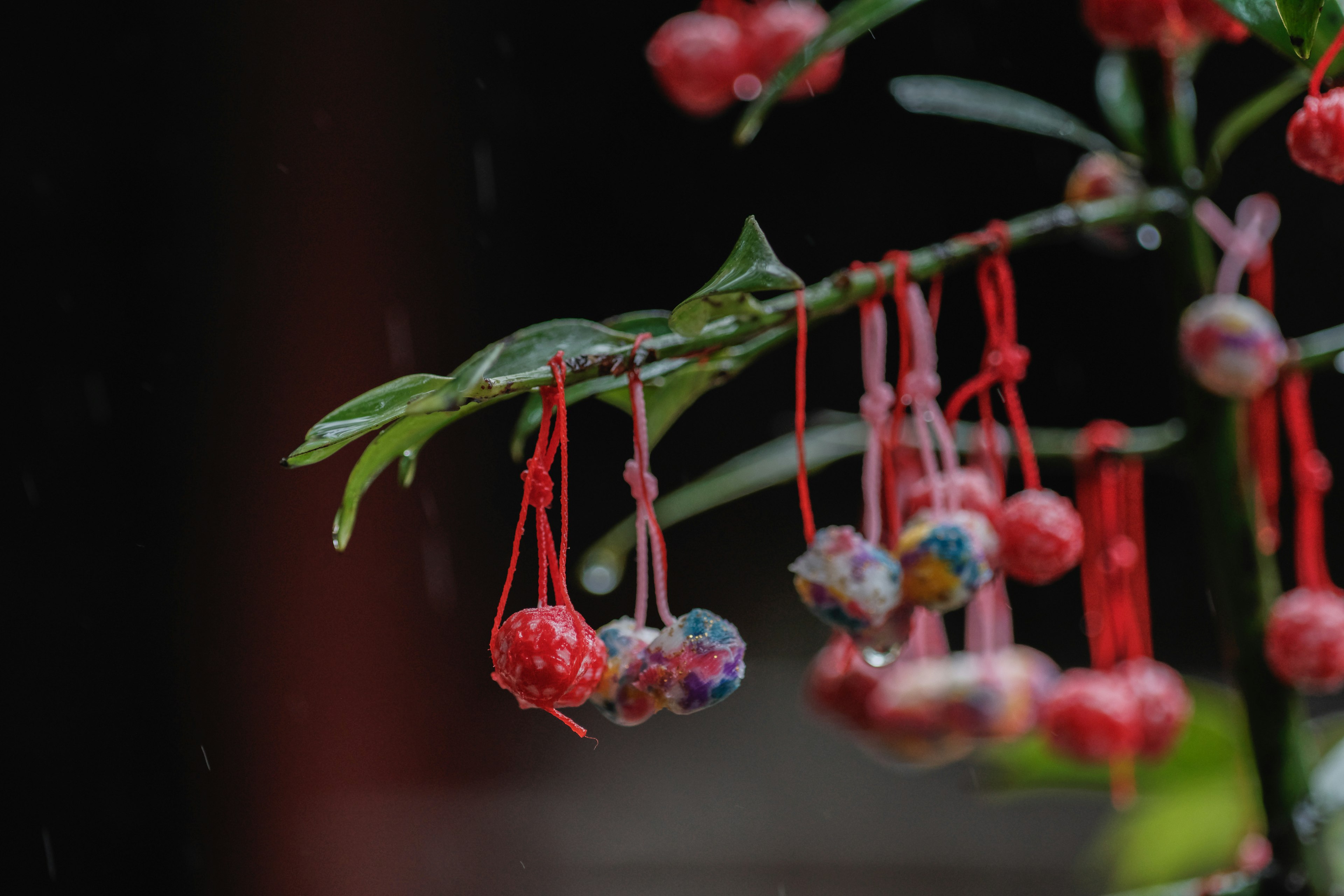 Gambar close-up dari cabang dengan daun hijau dan bola dekoratif merah