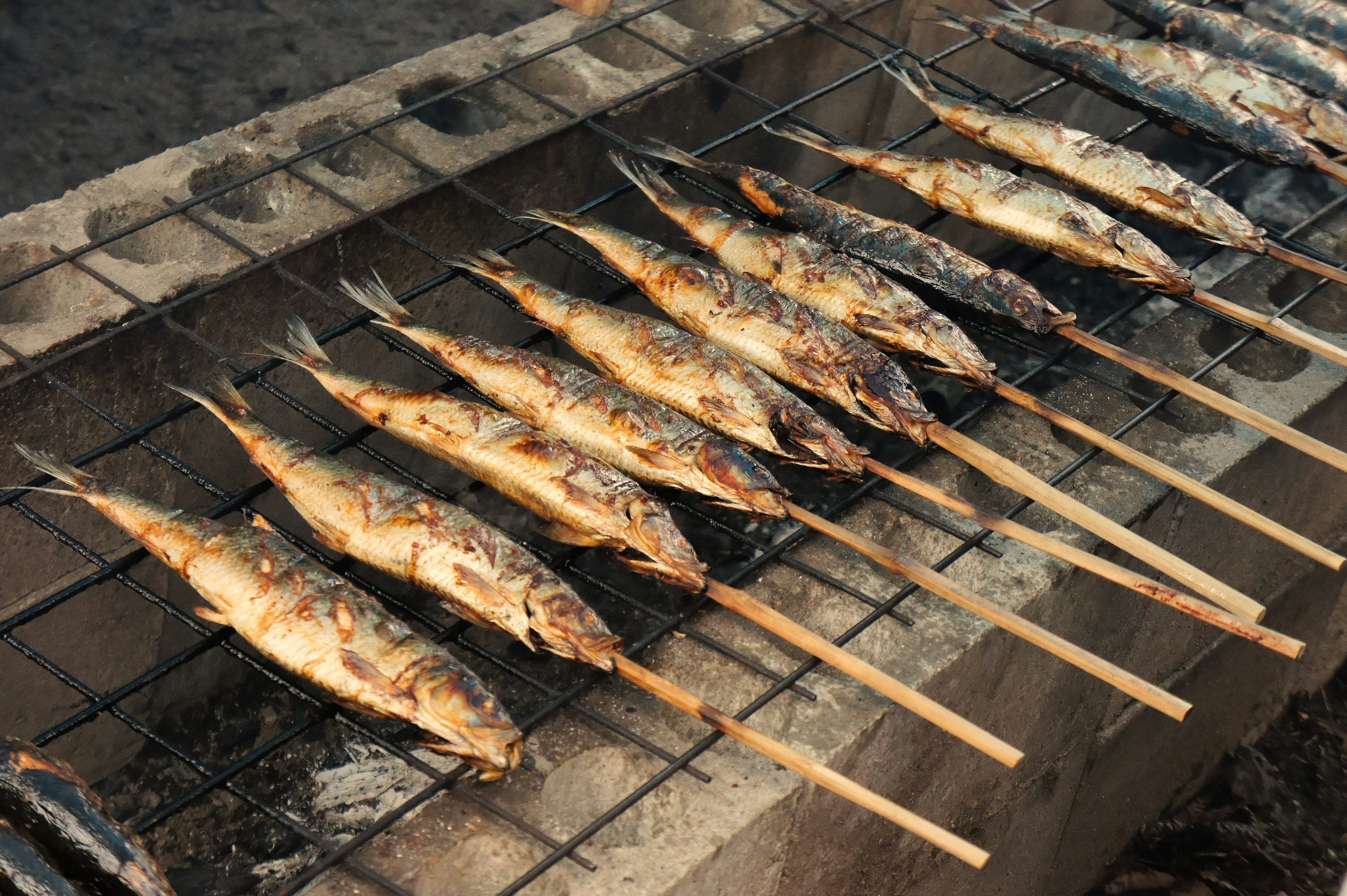 Pesce alla griglia su spiedini sopra una fiamma aperta