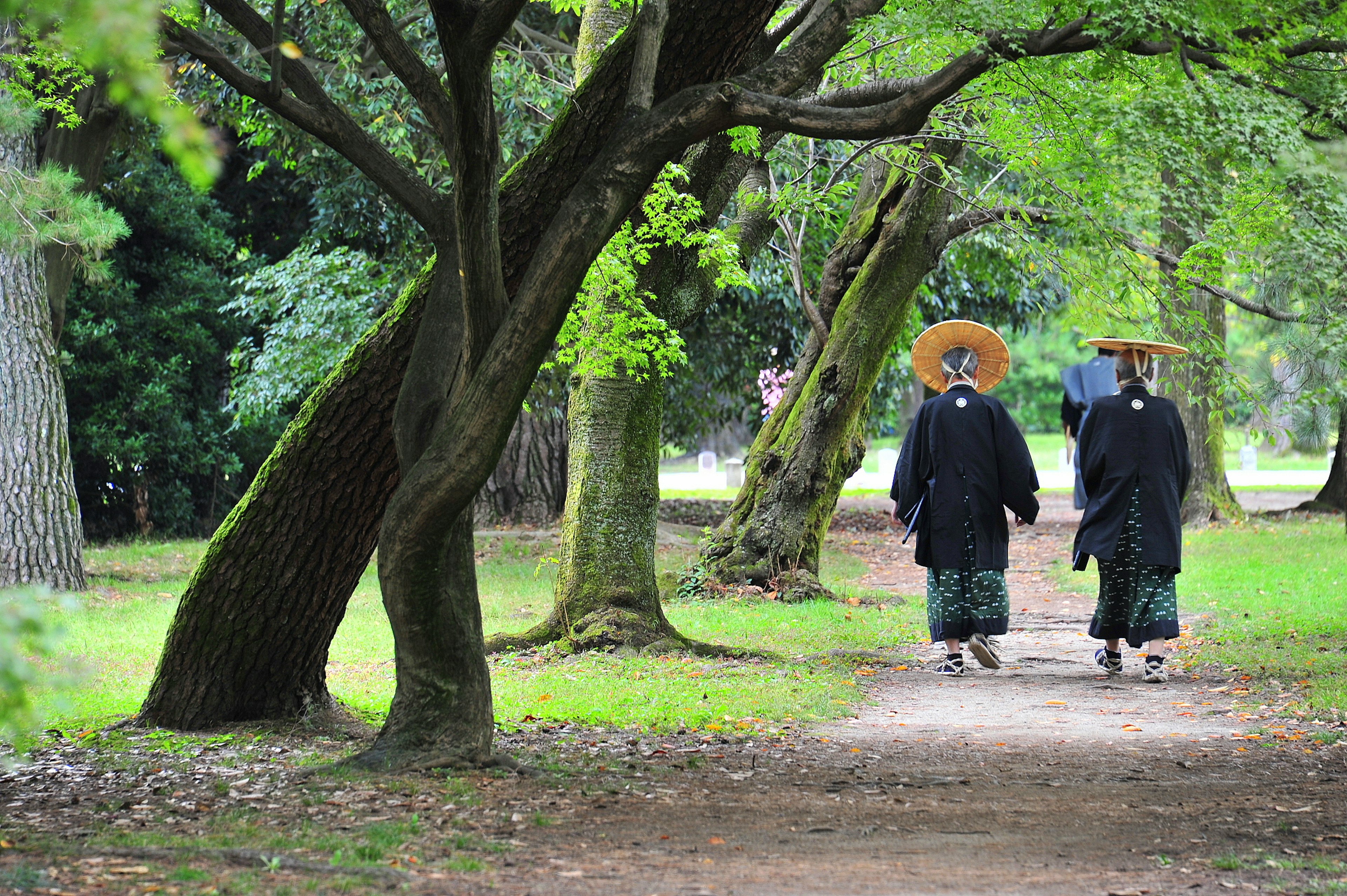 Dua orang berpakaian tradisional berjalan di taman yang rimbun