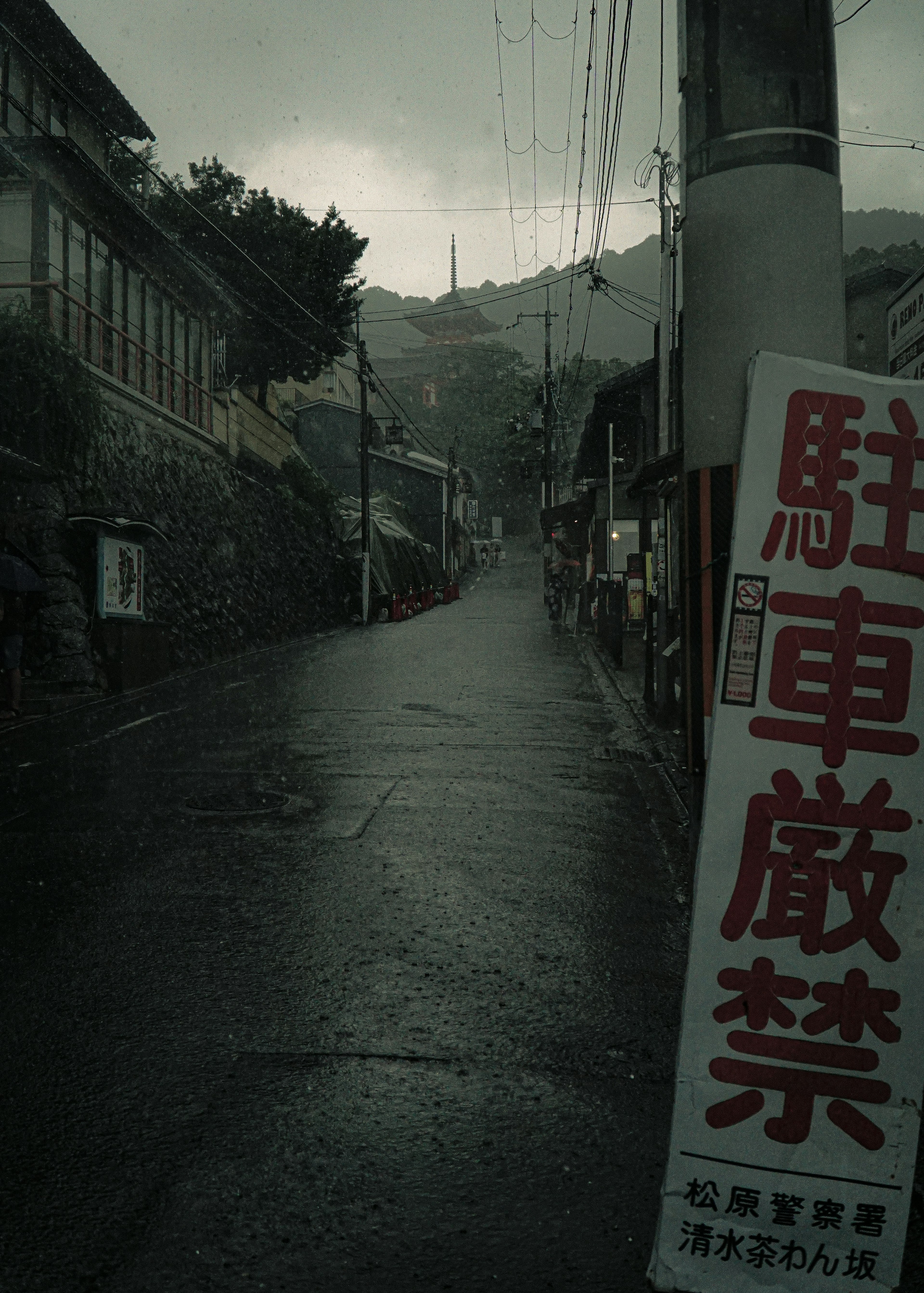 雨の降る細い道と禁止駐車の看板がある風景