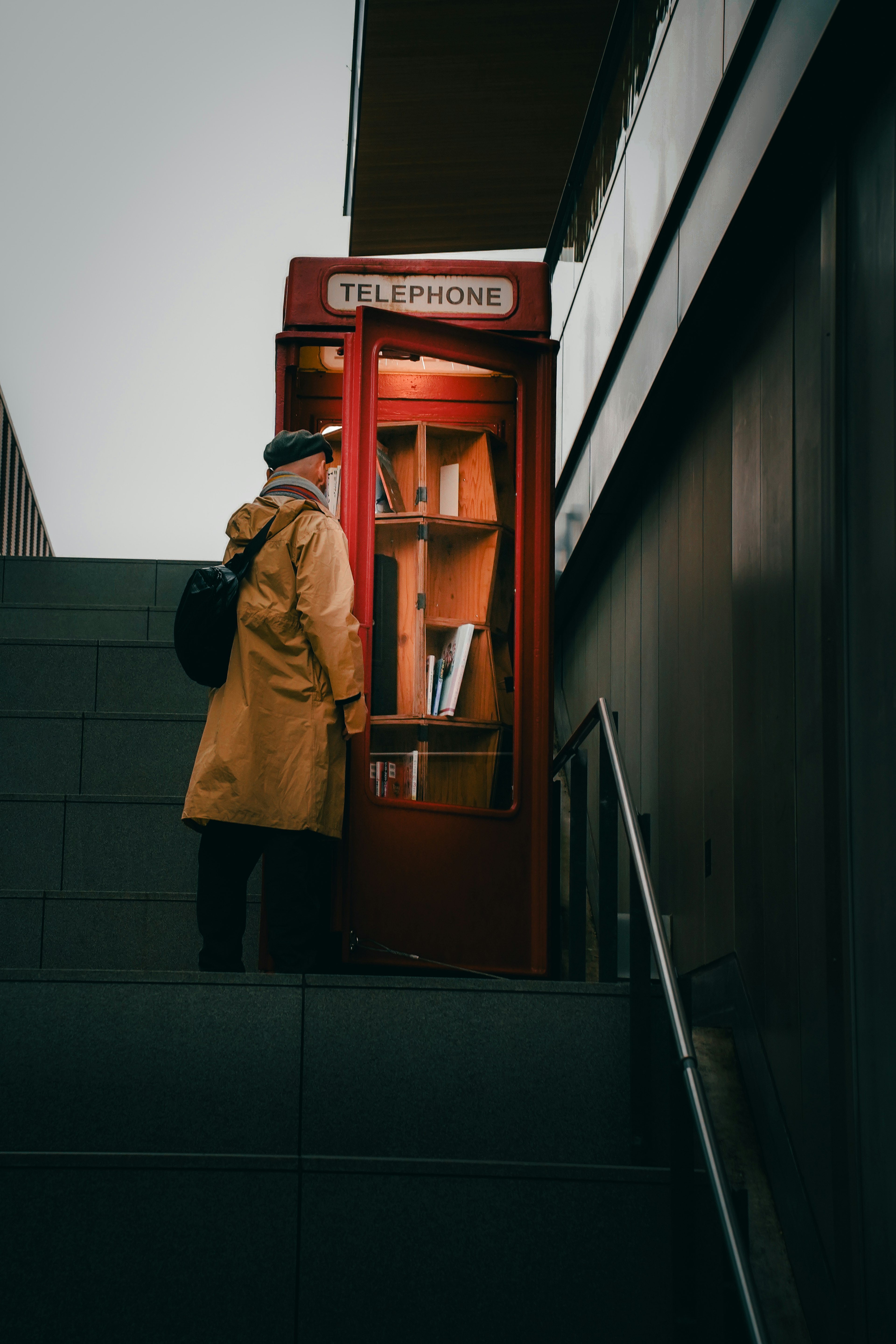 Man in yellow coat standing by a red telephone box