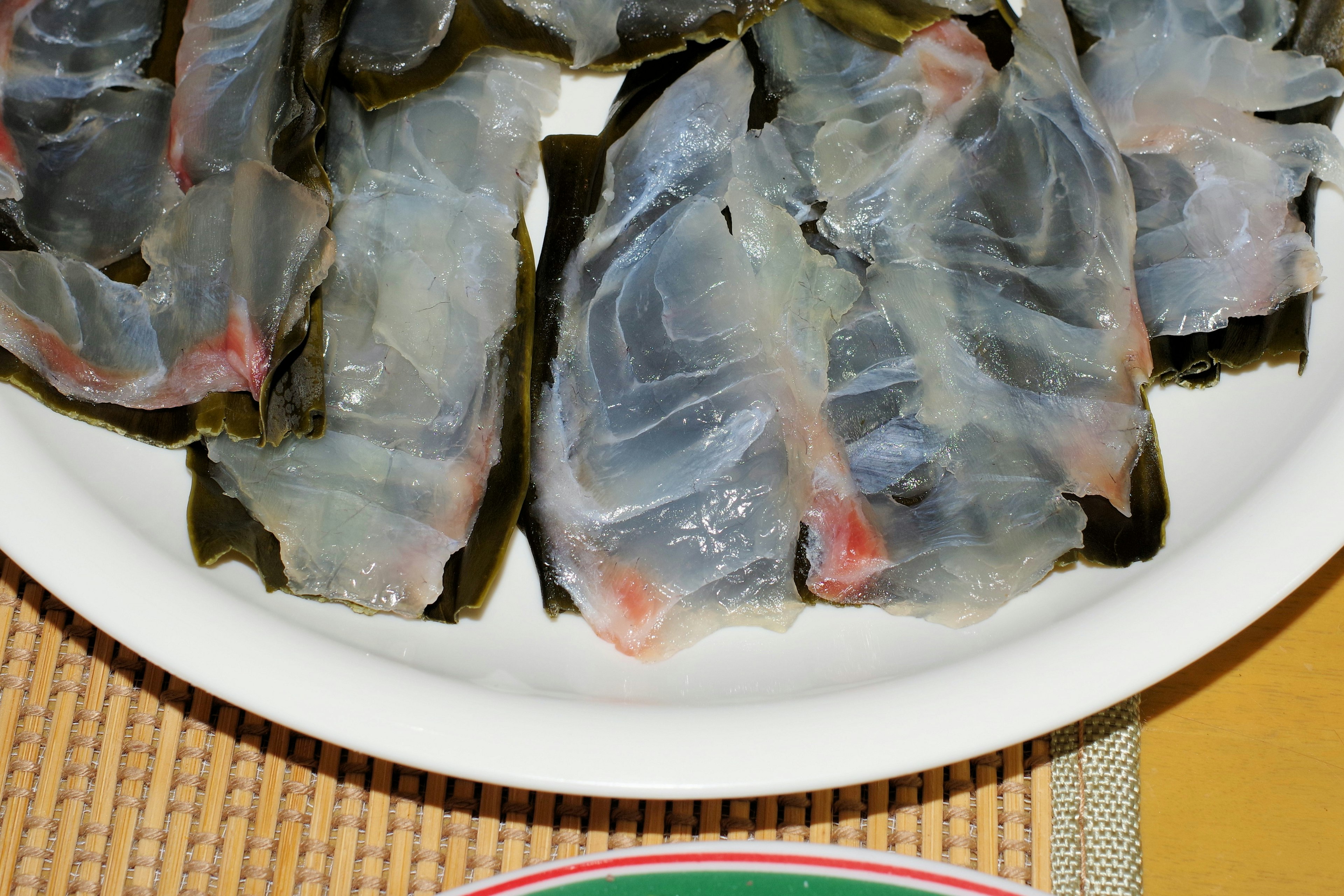 Sliced fish served on a plate with seaweed