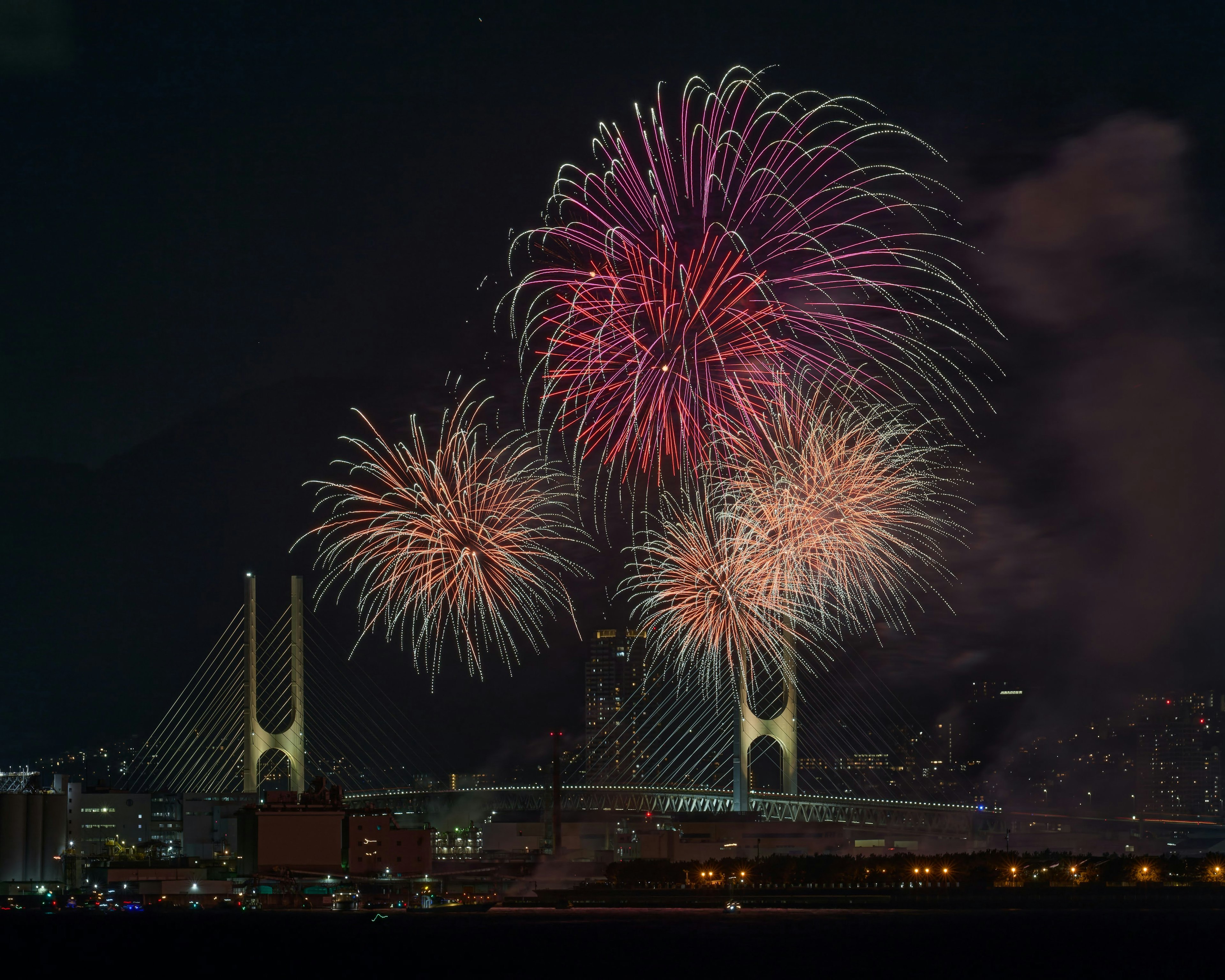 夜空に咲く色とりどりの花火と背景に見える橋