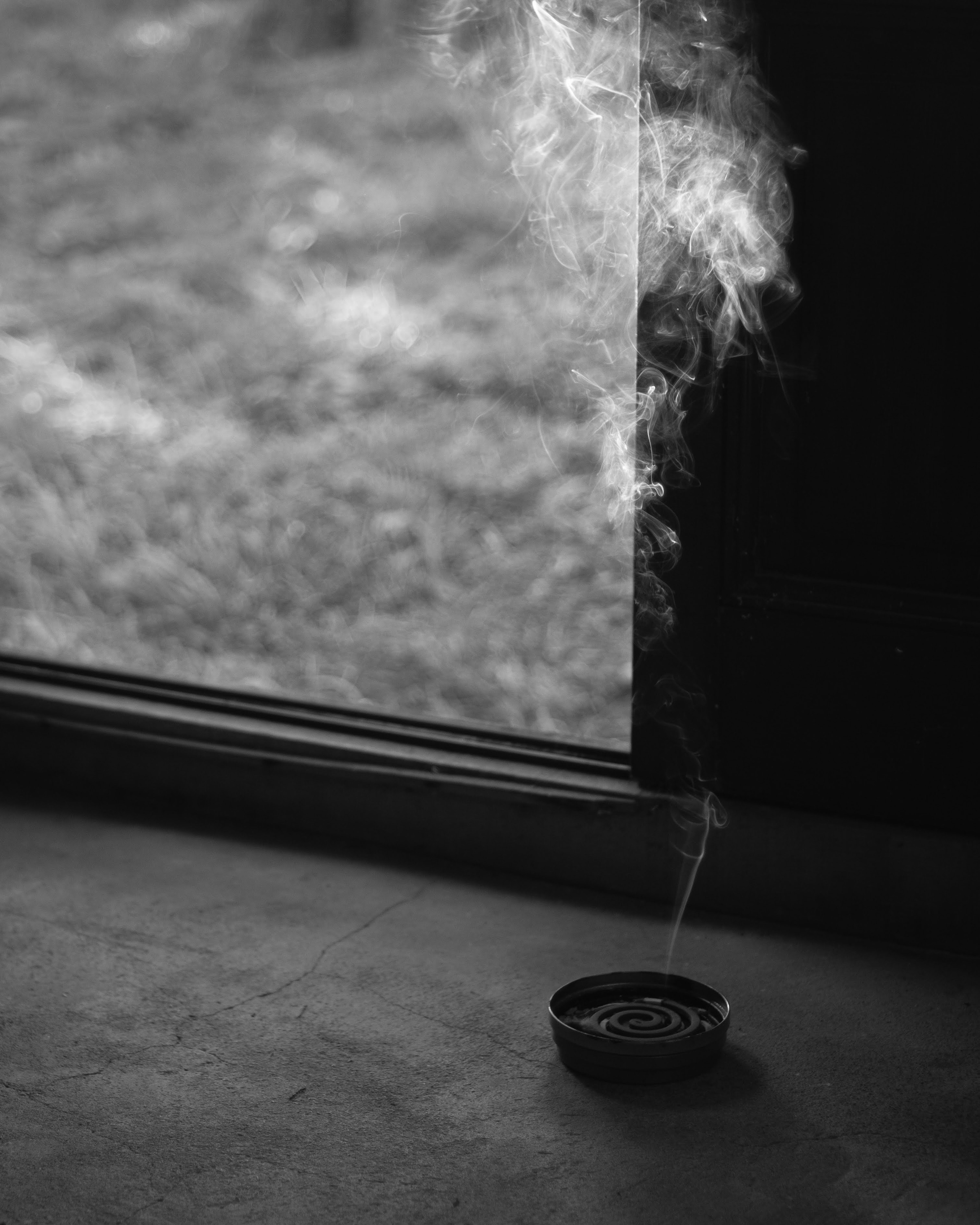 Incense smoke rising near an open window