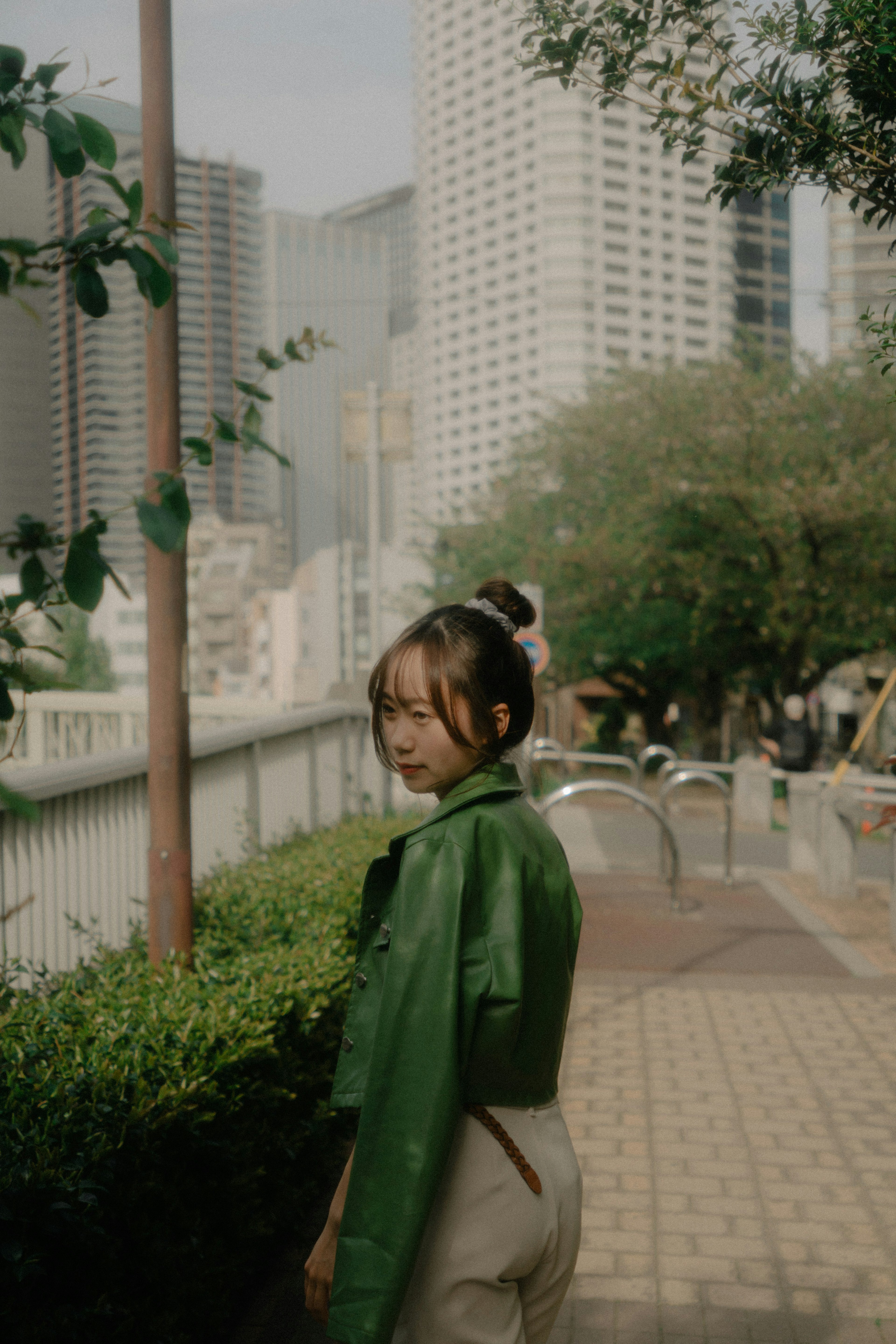 A woman in a green jacket smiling against an urban background