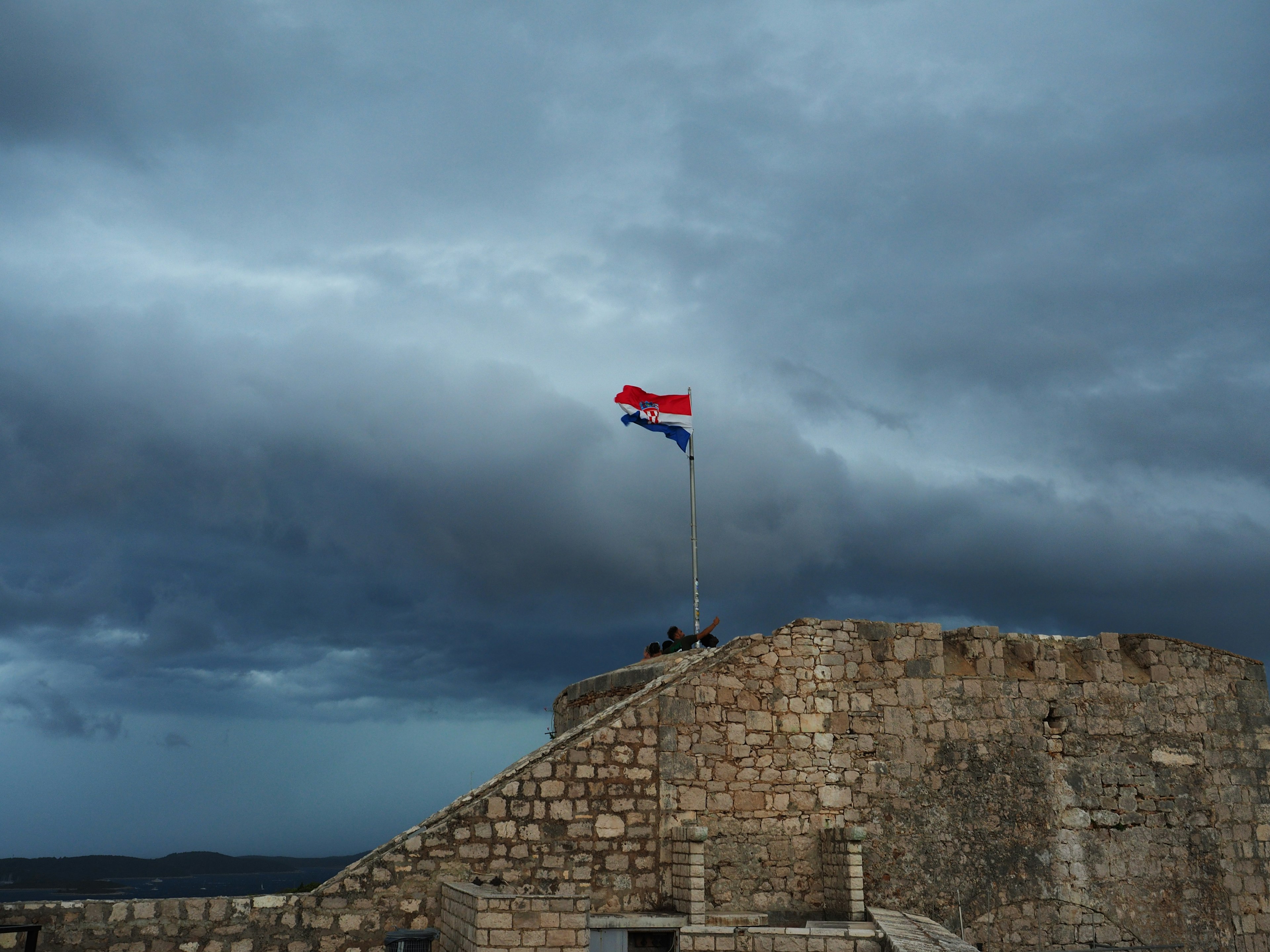 Drapeau croate flottant au sommet d'une forteresse en pierre sous un ciel nuageux