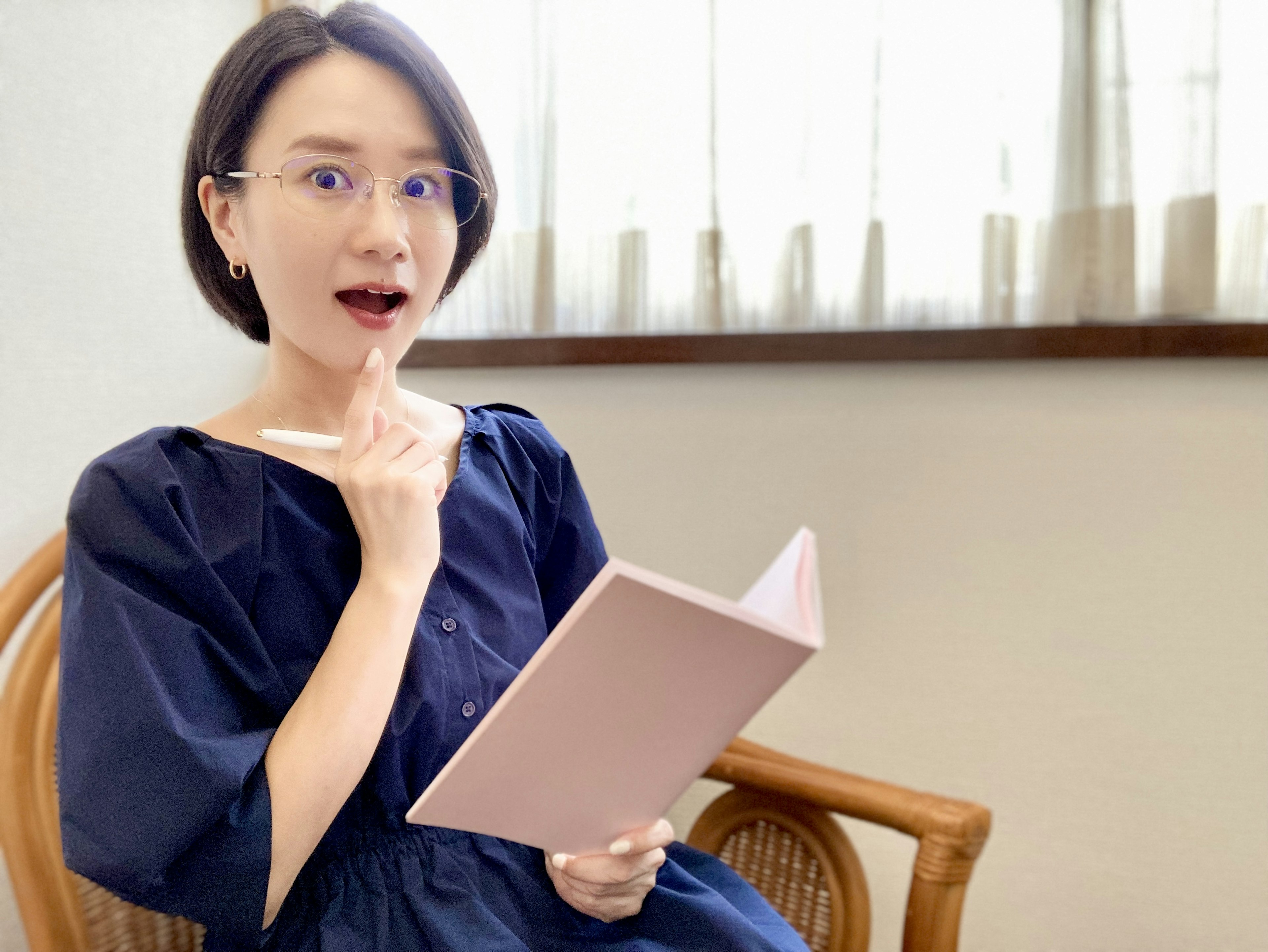 Young woman holding a notebook with a surprised expression while thinking