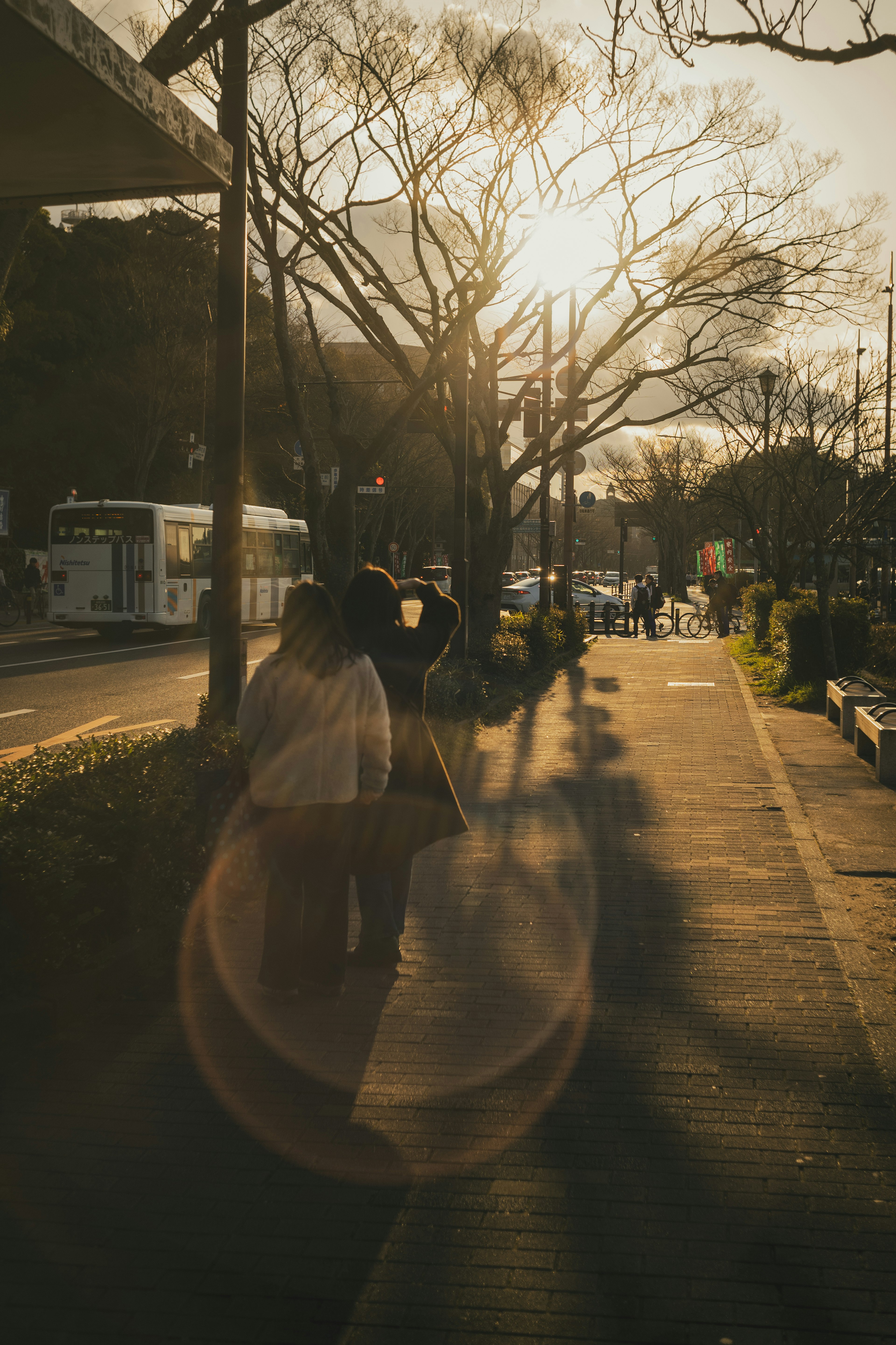 Persone che camminano su un marciapiede illuminato dal tramonto