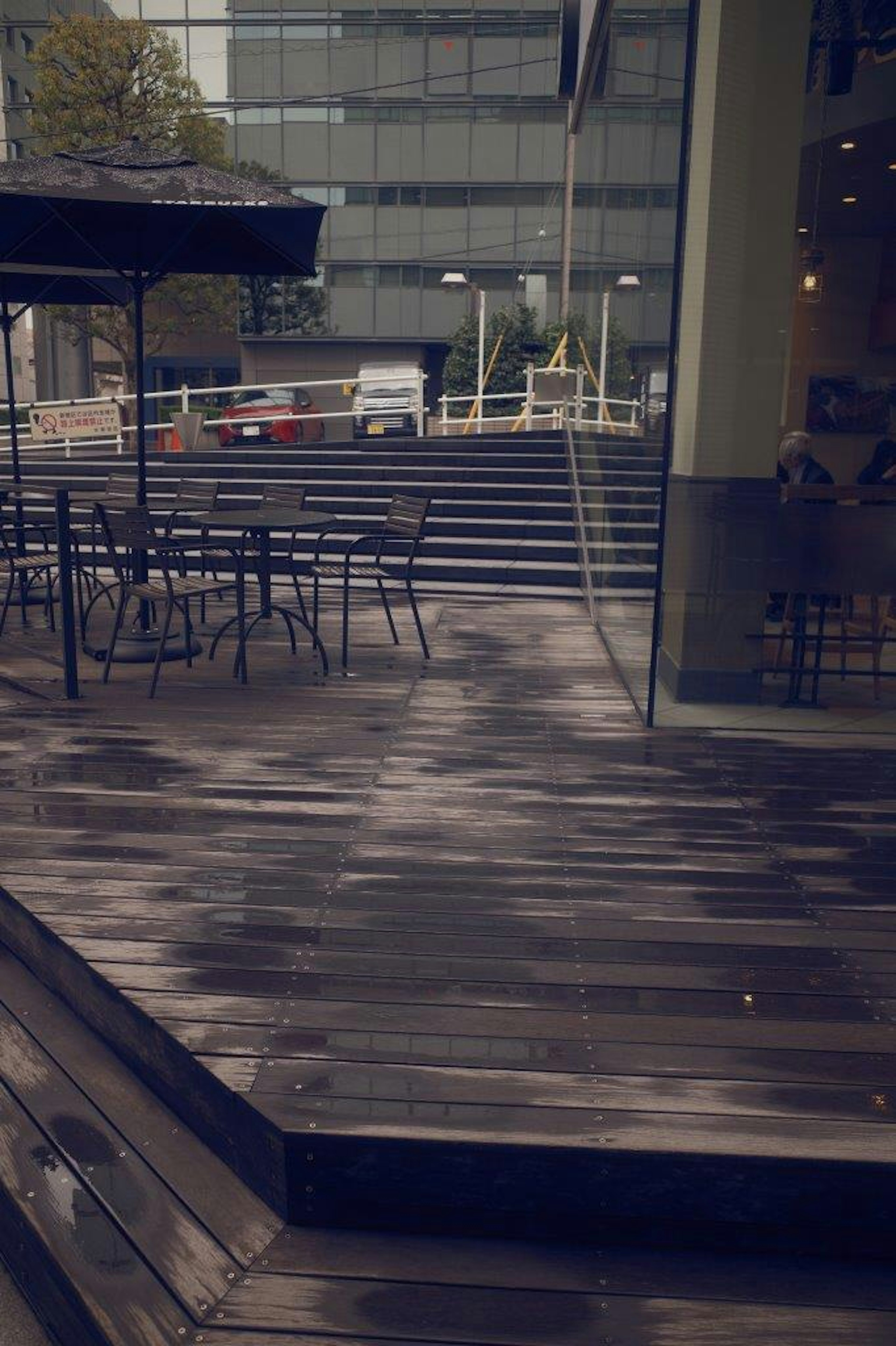 Terrazza in legno bagnata con tavoli da caffè dopo la pioggia