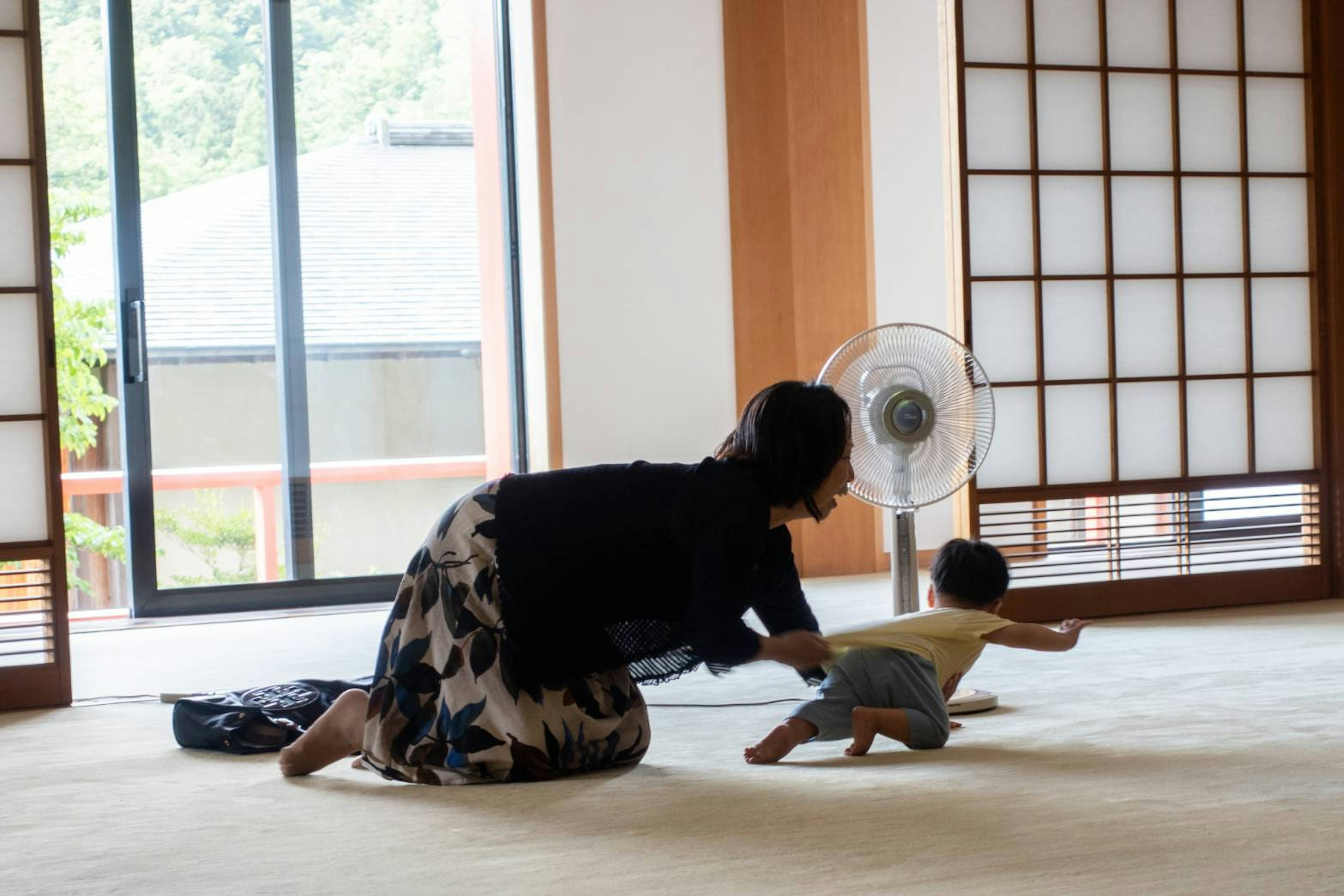 Seorang ibu mengejar bayinya di dalam ruangan bergaya Jepang