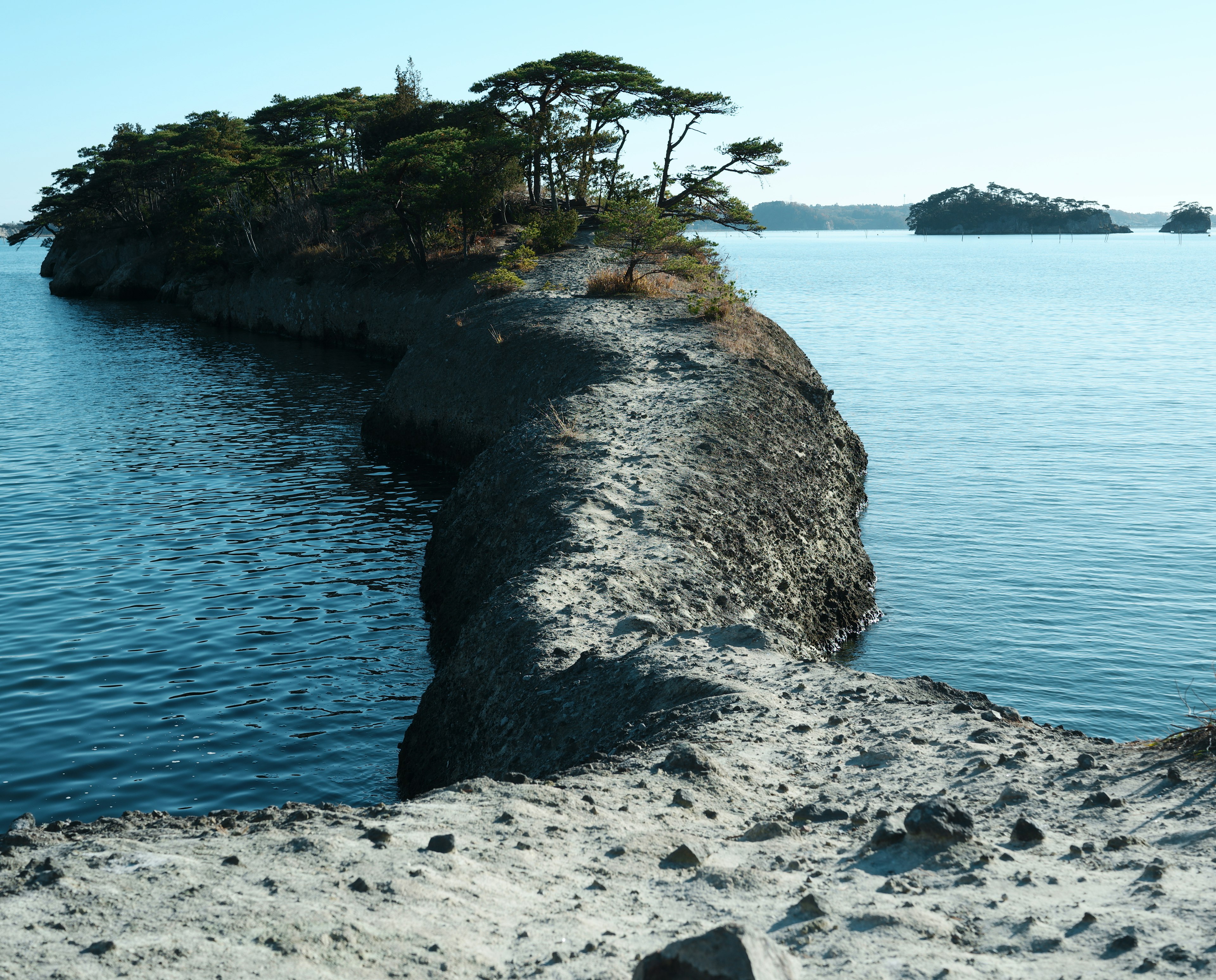 静かな水面に囲まれた島の砂浜道が見える風景