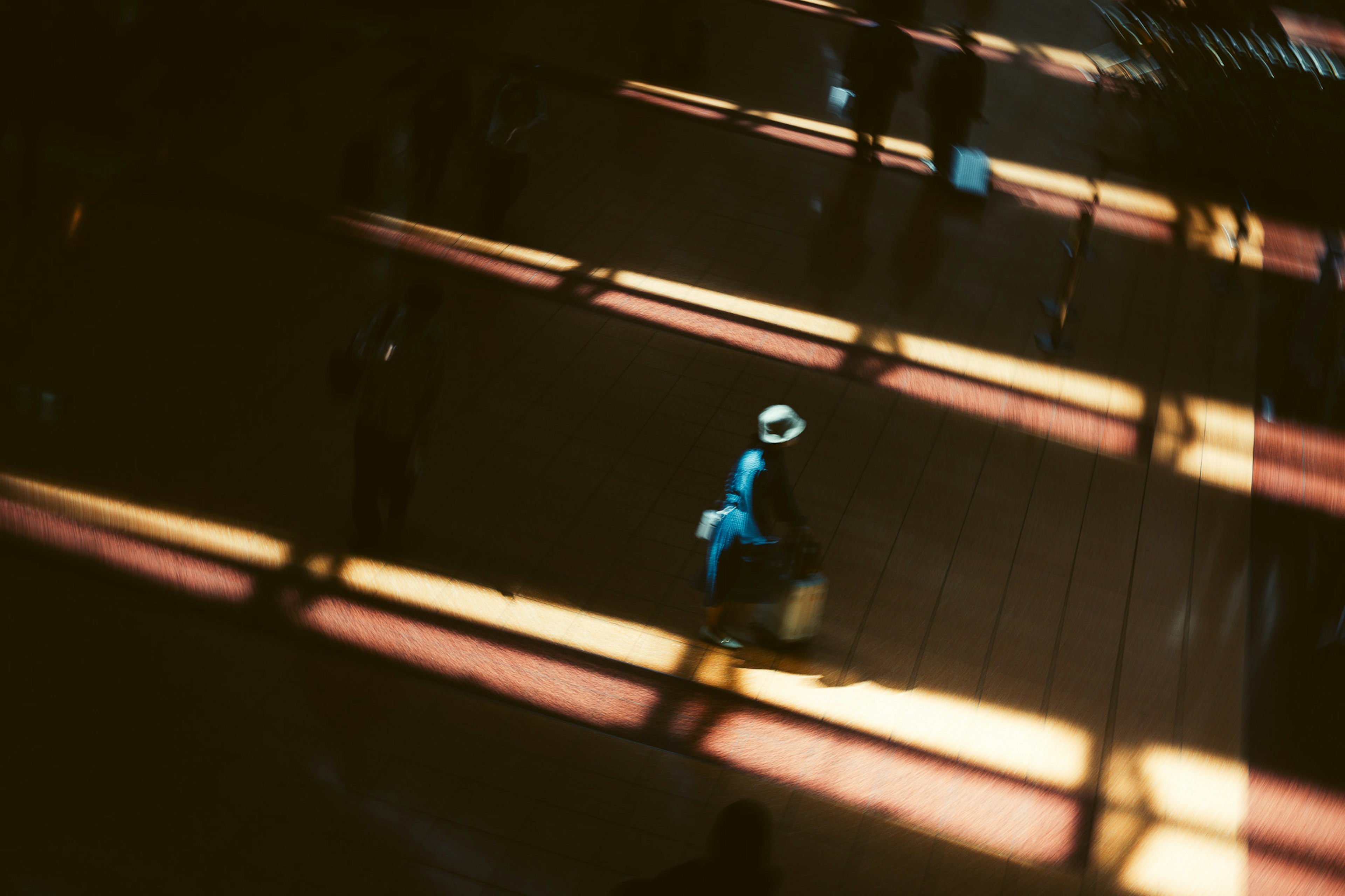 A person in blue clothing walking through stripes of light