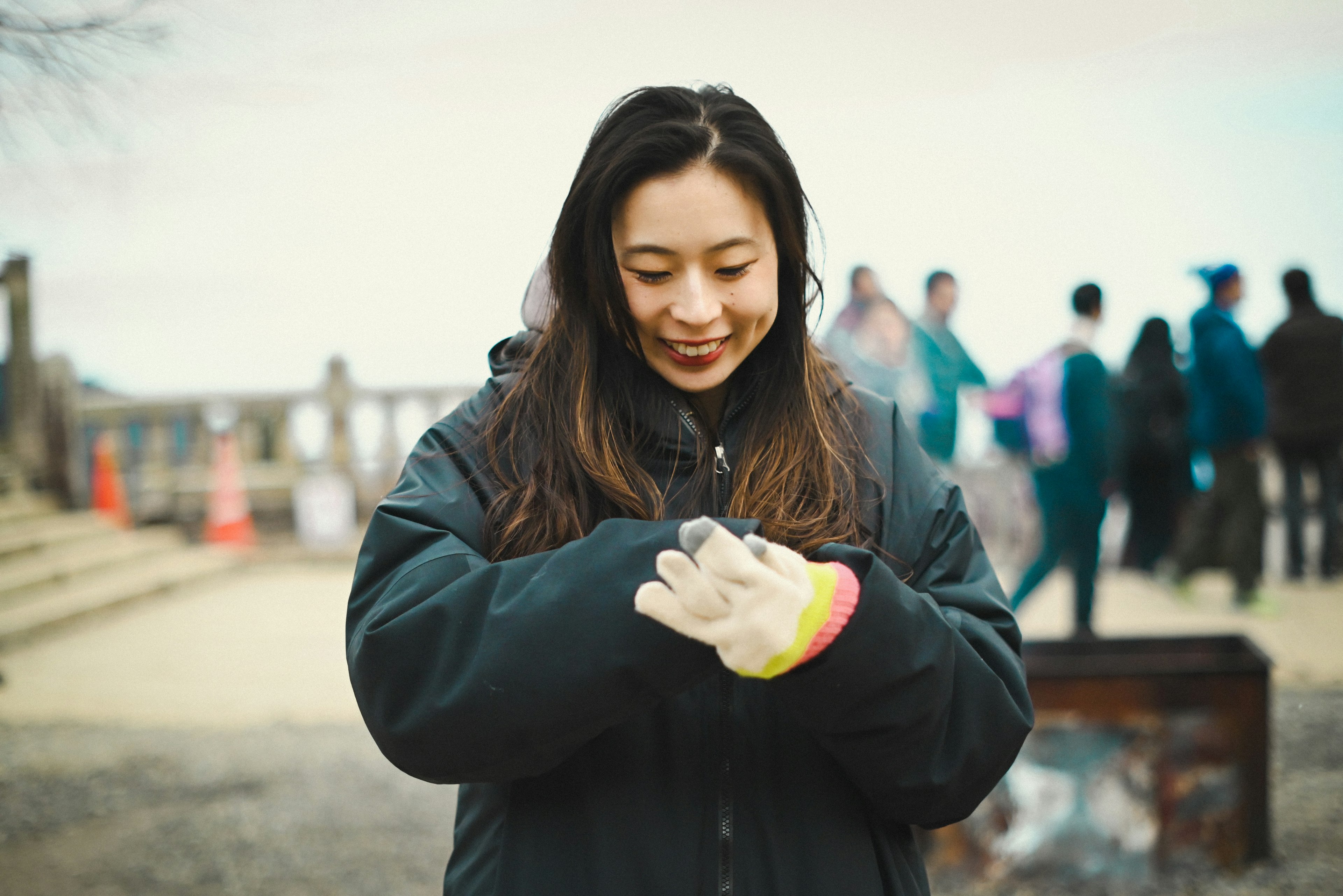 Femme souriante portant des gants avec des gens en arrière-plan